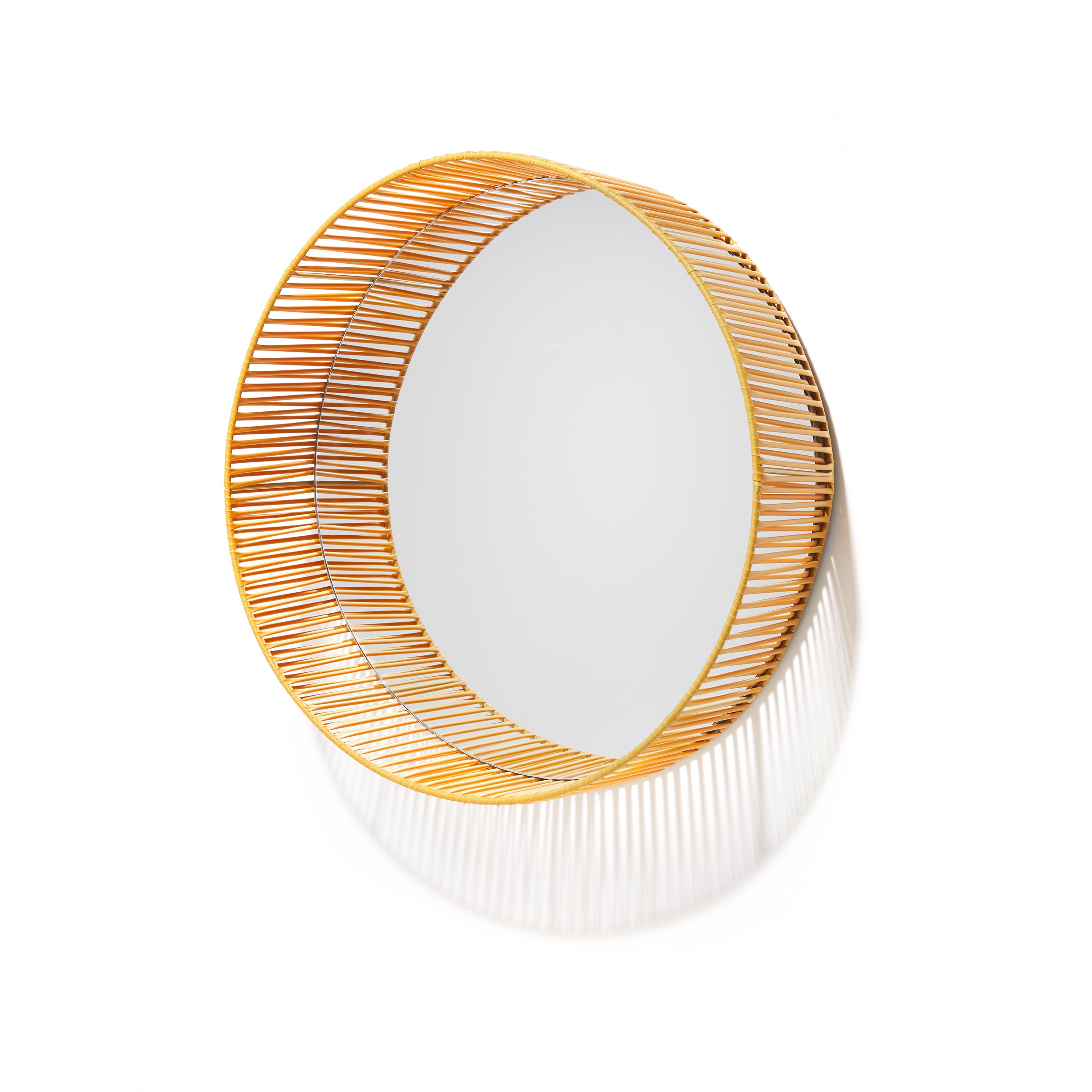 The Cesta Mirror by Ames features a round design with an intricately crafted frame of thin, evenly spaced golden rods that create a layered sunburst effect, elegantly blending vibrant colors against a white background.