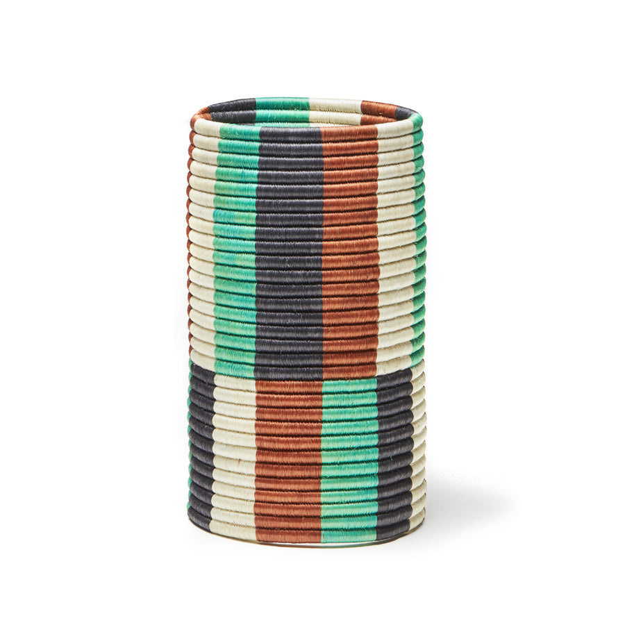 From Ames Choco Vases collection, this cylindrical vase features vertical rows of woven palm fibers in turquoise, brown, black, and cream stripes. It stands upright on a plain white background, exuding elegance and natural charm.