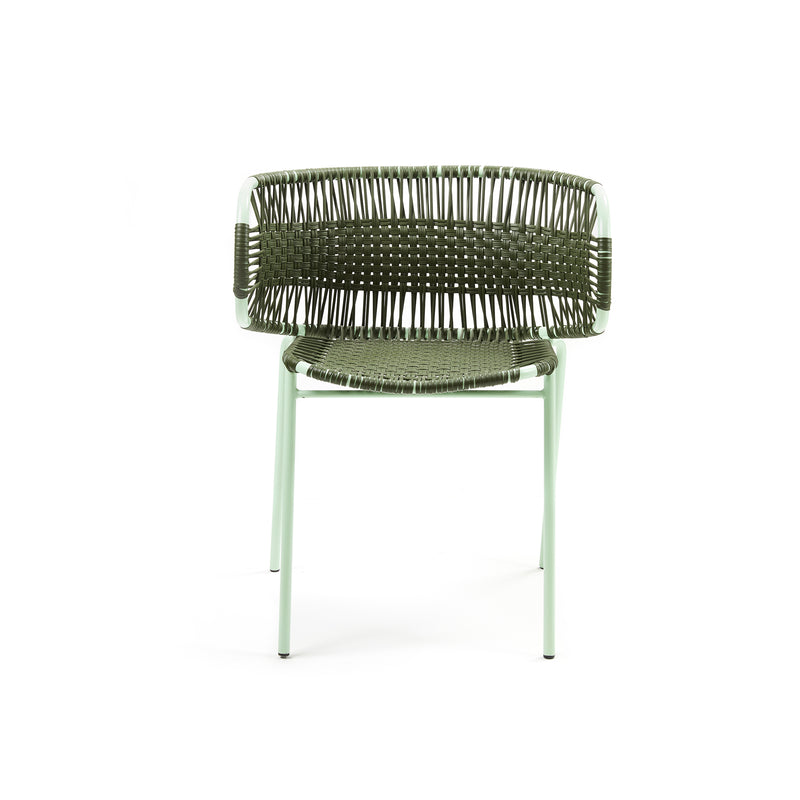 The Cielo Armchair by Ames is a versatile outdoor chair featuring a woven back and seat with traditional techniques, complemented by sleek pale green metal legs and armrests. Perfect for indoor and outdoor use, it adds texture and style to any space.