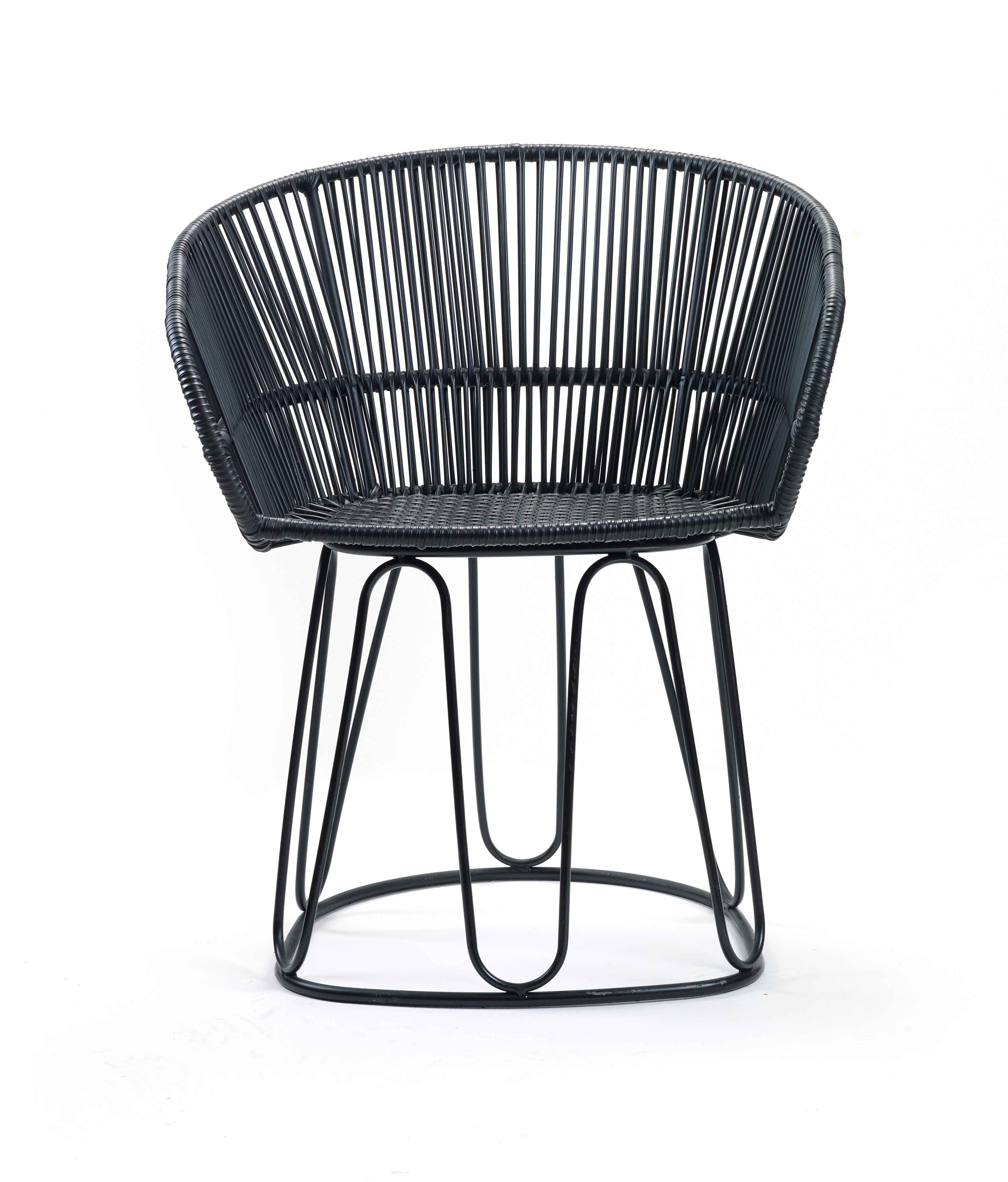 This contemporary chair from the Circo Chairs collection by Ames features an open-back design made of black rattan. Handcrafted by Colombian artisans, it rests on a sleek black metal frame, offering a modern look against a white background.