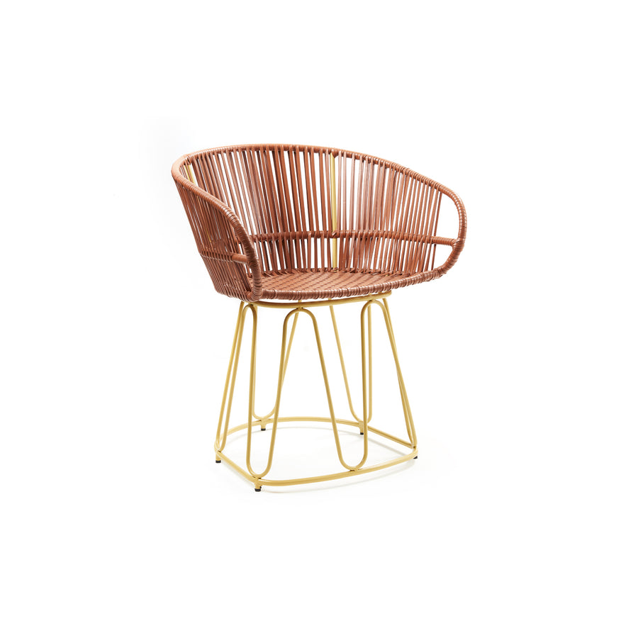 From the CIRCO collection by Ames, the modern Circo Leather Dining Chair features a curved rattan seat and backrest handcrafted by Colombian artisans. With a sleek gold metal frame and circular base, it blends natural and contemporary elements seamlessly.