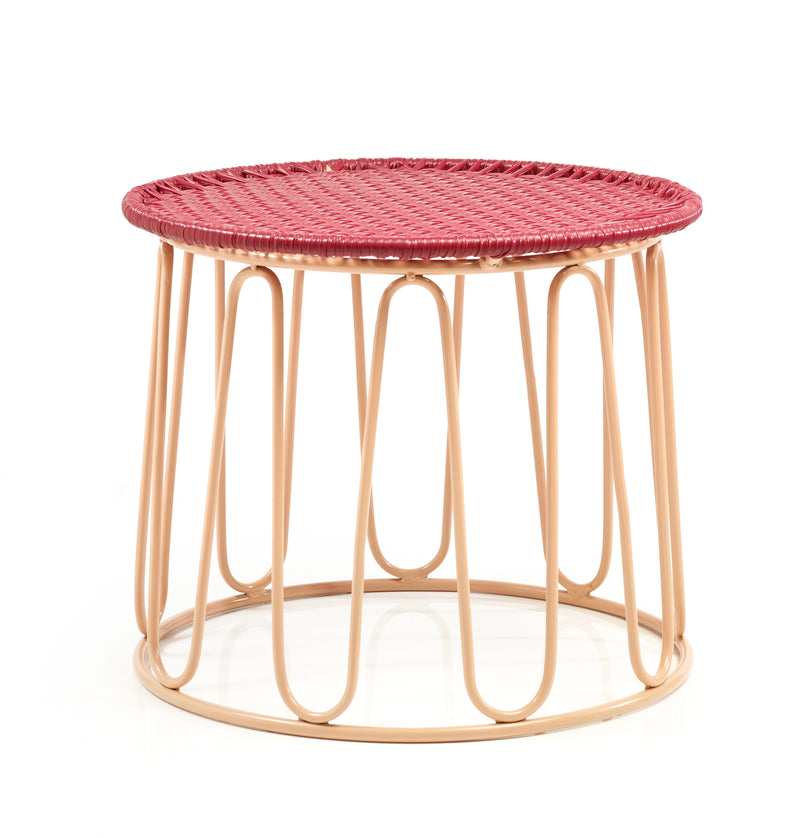The Ames Circo Side Table by Ames is a small round table with a red woven top and a beige metal frame featuring curved vertical supports, inspired by handcrafted Colombian furniture, shown against a white background.