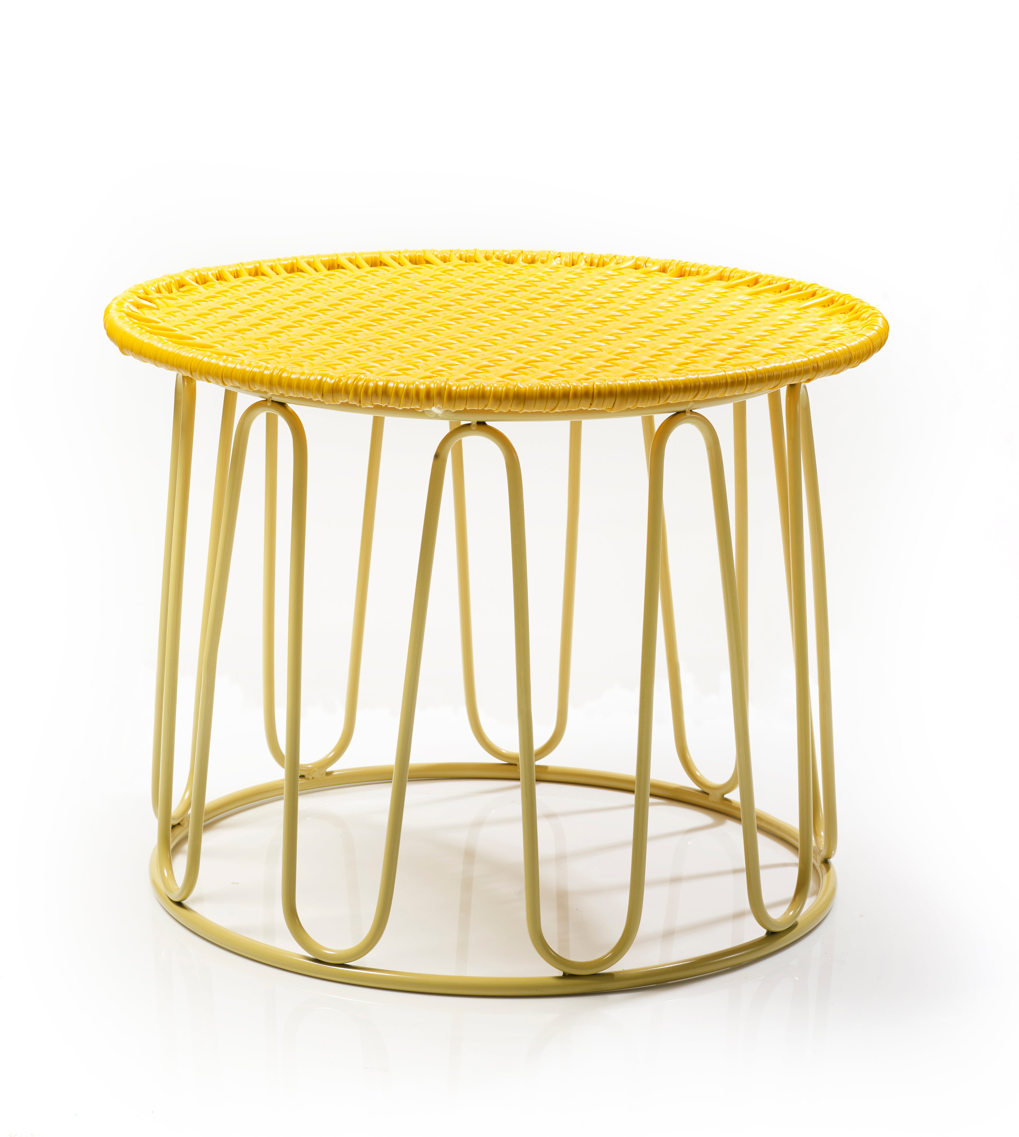 The Ames Circo Side Table by Ames is a handcrafted Colombian piece with a round yellow woven top and an open metal base with curved, looped legs, shown here against a white background.