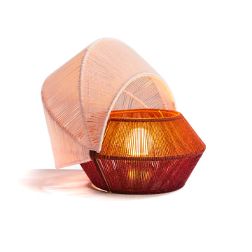 The Ames Farol Side Lamp by Ames features a geometric hexagonal base in red and orange and a translucent curved mesh shade, inspired by Farols table lamps, shown glowing against a white background.