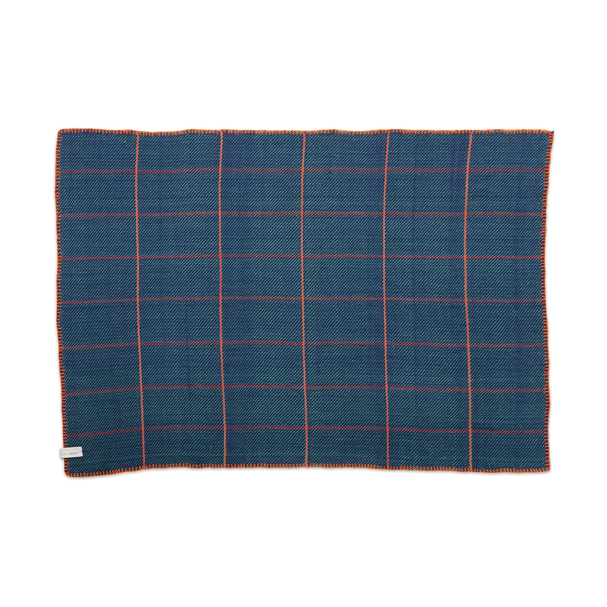 The Ames Manta Plaid by Ames features a blue rectangular design with an orange and white grid, orange-edged stitching, and a small fabric tag—highlighting traditional Colombian craftsmanship and displayed flat on a white background.