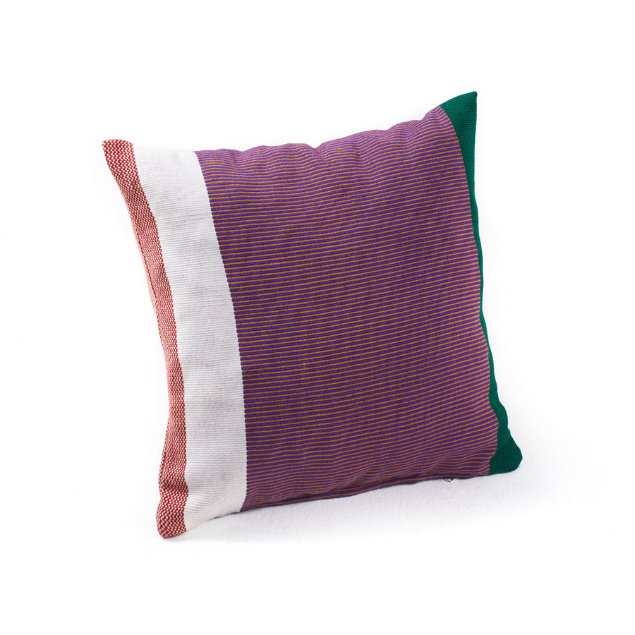 Explore the Maraca Cushion by Ames, a square creation of hand-woven cotton featuring bold red and purple vertical stripes accented with white and dark green edges. Crafted with natural dyes, this striking piece stands out beautifully against a plain white background.