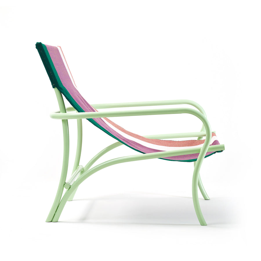 The Maraca Lounge Chair by Ames features a light green, curved metal frame and a seat-back woven in pink and green fabric reminiscent of Colombian hammocks. Its stylish, modern design is showcased against a plain white background.