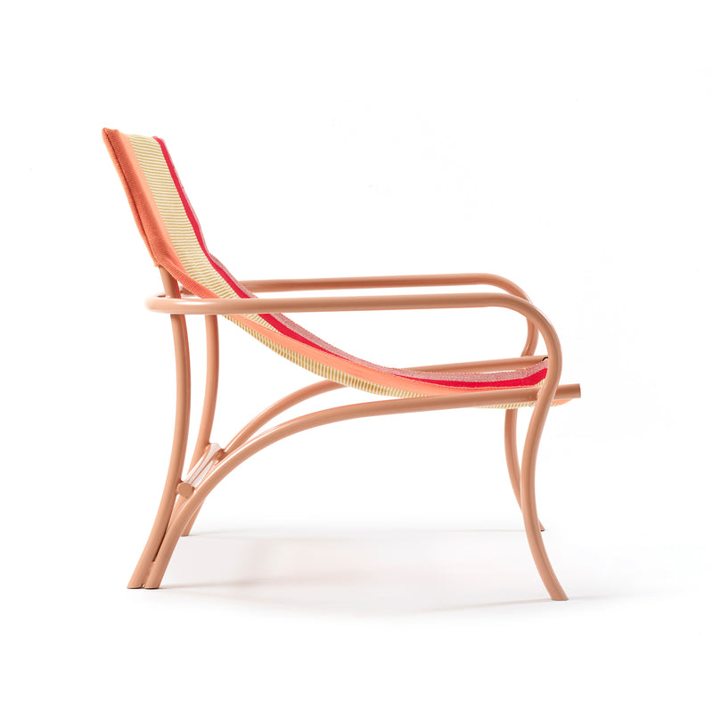 Side view of the Ames Maraca Lounge Chair showcasing a sleek tan frame and woven red/beige seat and backrest. The chair has curved armrests with ethnic designs in a minimalist style, set against a white background.