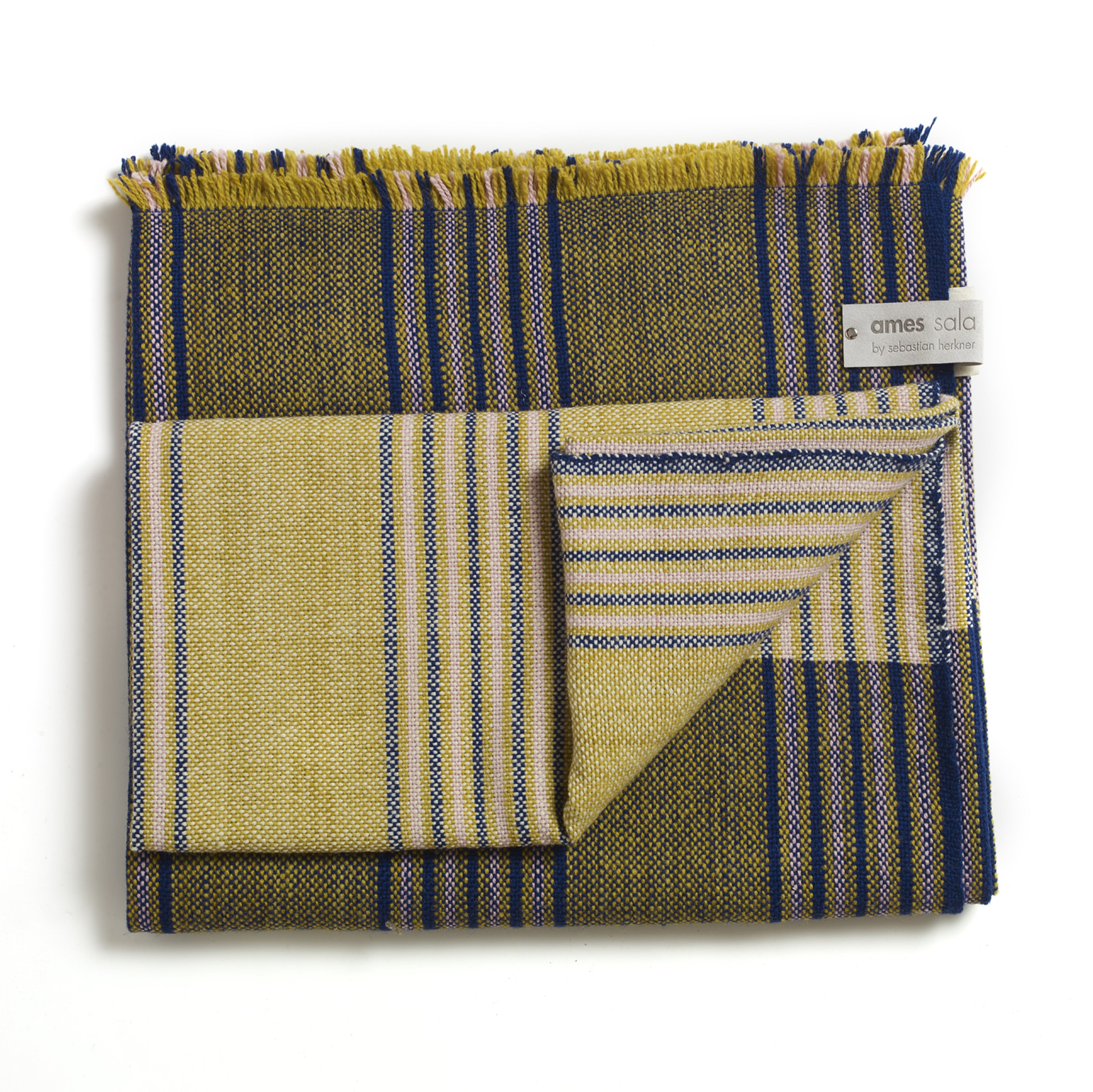 The Ames Mulera Throw by Ames features olive green, yellow, and blue stripes with fringed edges. Neatly folded, it displays both its striped front and solid back, with a corner label that reads "ames sala by sebastian herkner.