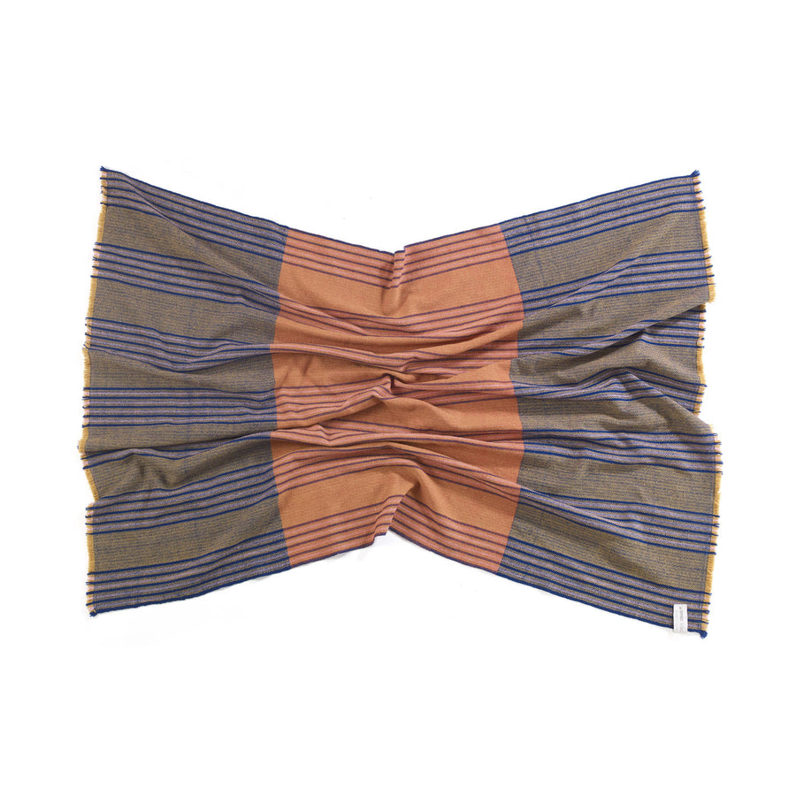 The Ames Mulera Throw by Ames is a rectangular fabric piece featuring blue and olive stripes on the sides, with a wide, solid brownish-orange stripe in the center, shown flat with gentle gathered folds.