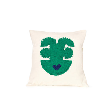 The Ames Nido Qeztal pillow, part of our handmade collection, features a square white design with a green abstract face showing two eyes, a nose, and a mouth illustrated by a small blue heart, adding artistic flair to any space.