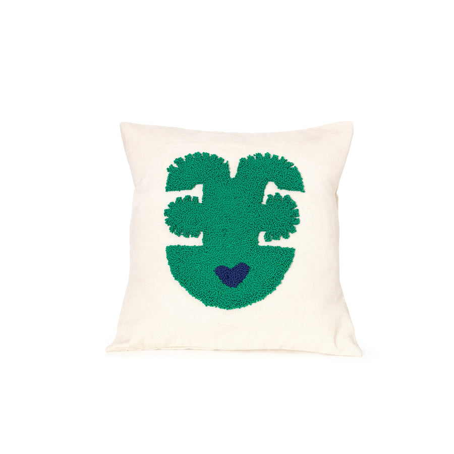 The Ames Nido Qeztal pillow, part of our handmade collection, features a square white design with a green abstract face showing two eyes, a nose, and a mouth illustrated by a small blue heart, adding artistic flair to any space.