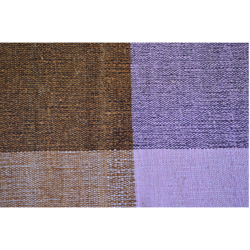 Ames Nobsa Rug showcases a close-up of a checkerboard pattern, featuring alternating brown and purple squares. This hand-woven textile highlights the textured weave typical of the wool artistry from Colombias Nobsa city.