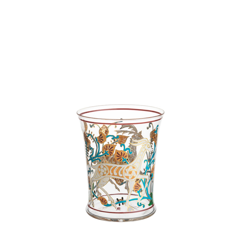 The Alhambra Tumbler by Lobmeyr showcases intricate, colorful patterns with a stylized animal, leaves, and floral designs in gold, teal, and rust. It features a tapering wide base and a thin red rim accent, reflecting Franz Schmoranzs artistic style.