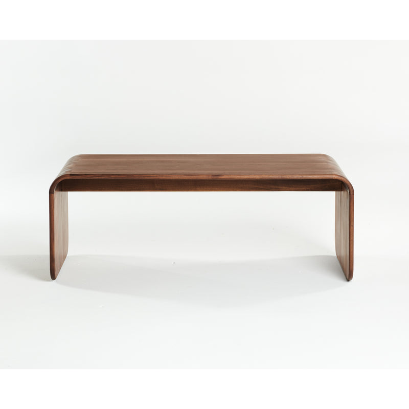The ENY Coffee Table by Artisan is a minimalist piece crafted from solid wood, featuring a smooth, curved design and finished with natural oils. It elegantly stands against a plain white background, emphasizing its eco-friendly charm.