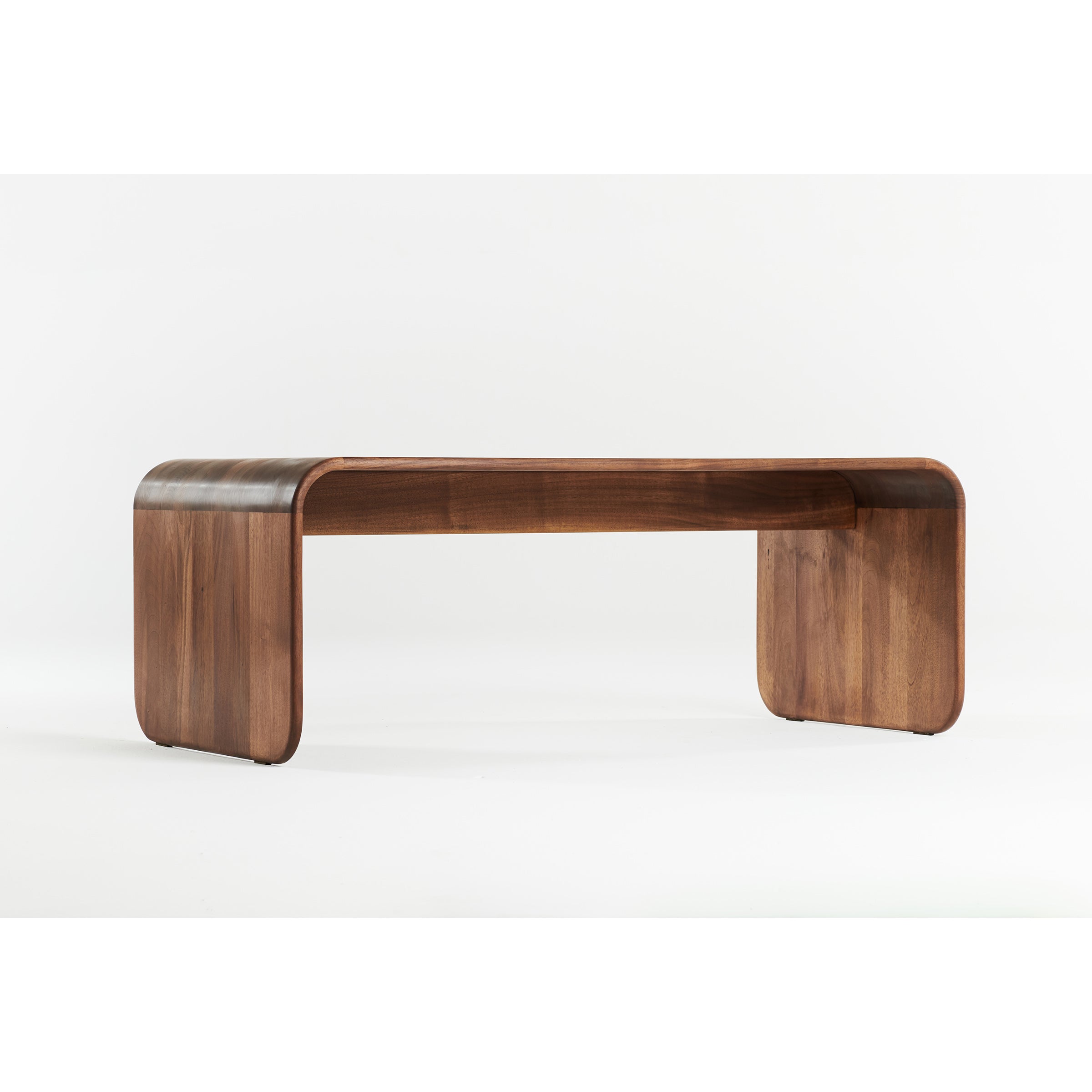 The ENY Coffee Table by Artisan features a sleek, modern design with curved edges crafted from dark solid wood treated with natural oils. It possesses a minimalist aesthetic and exudes an eco-friendly charm against a plain white background.