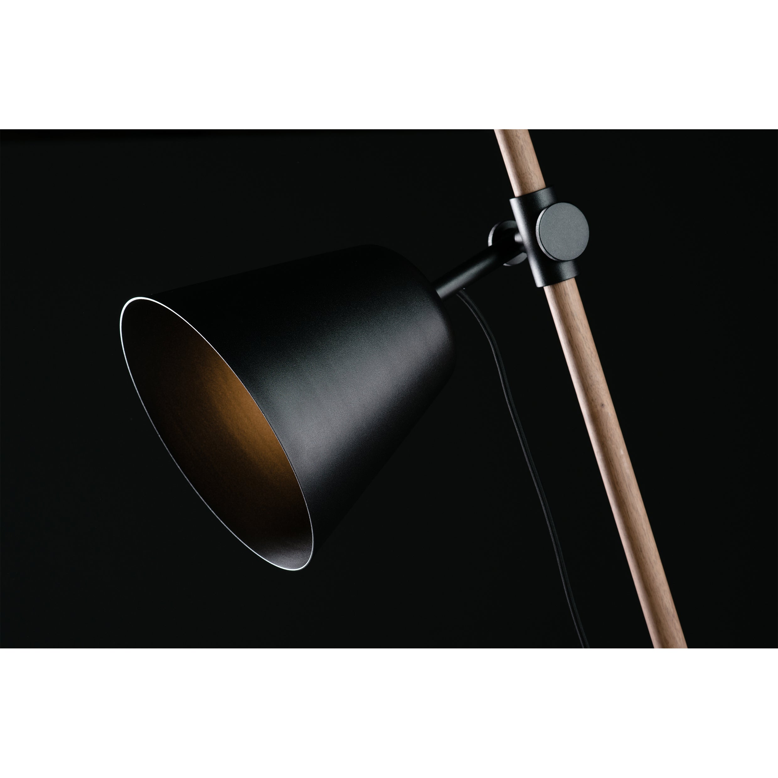 Close-up of Artisans INSERT Table Lamp, featuring a modern black conical shade and solid wood stand finished with natural oils, angled downward against a dark background.