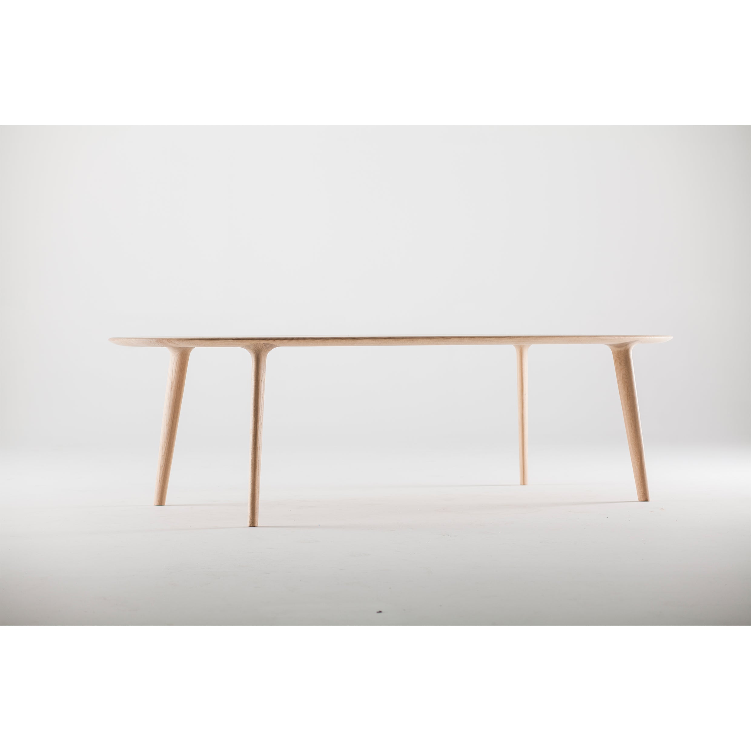 The LUC Table by Artisan is a minimalist wooden piece featuring slender legs and a smooth surface, epitomizing artisan craftsmanship. Its refined wood finishes contrast beautifully against the plain, white background.