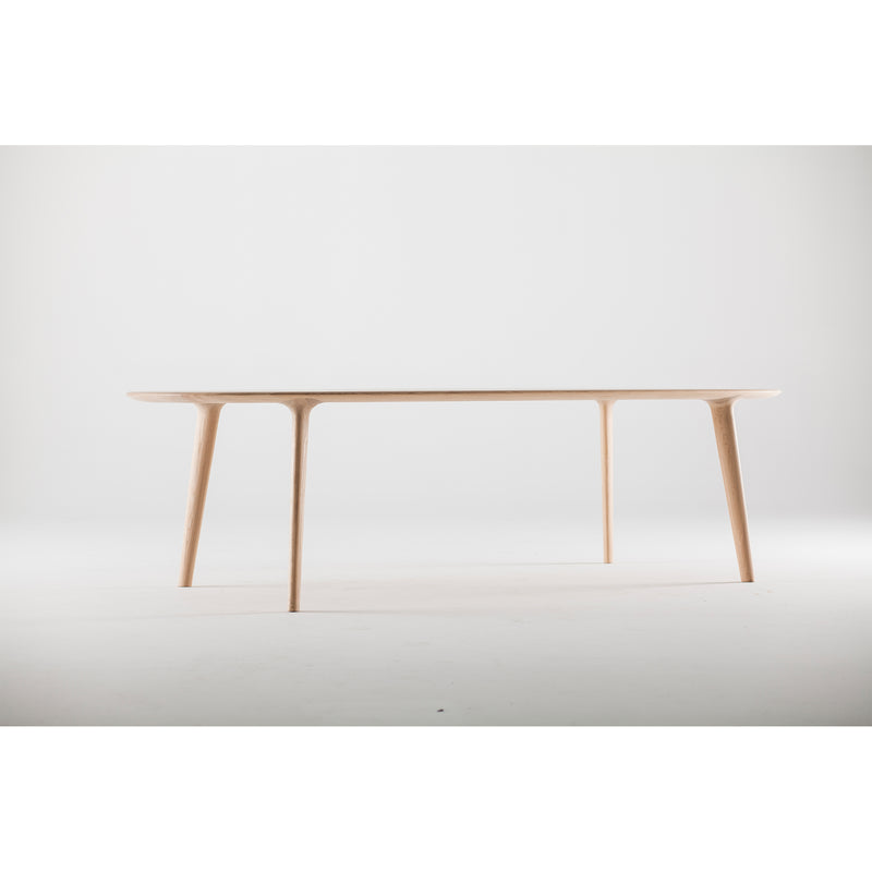 The LUC Table by Artisan is a minimalist wooden piece featuring slender legs and a smooth surface, epitomizing artisan craftsmanship. Its refined wood finishes contrast beautifully against the plain, white background.