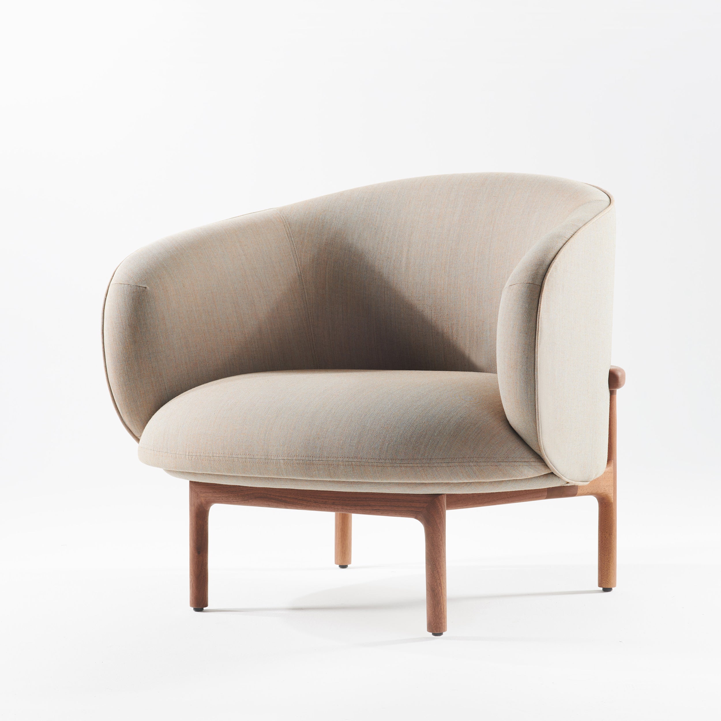 Part of the Artisan MELA Collection, the MELA Lounge Chair Trimmed features a modern, light gray upholstery with a curved backrest and soft padding. With wooden legs and a sleek, mid-century inspired design, it elegantly stands against a white background.