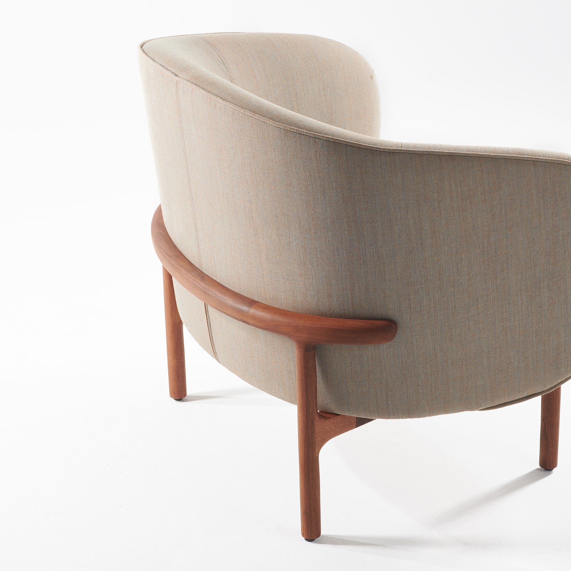 The MELA Lounge Chair Trimmed by Artisan showcases mid-century elegance with its modern curved beige design, wooden legs, and smooth back support. Set against a white background, it embodies timeless sophistication.