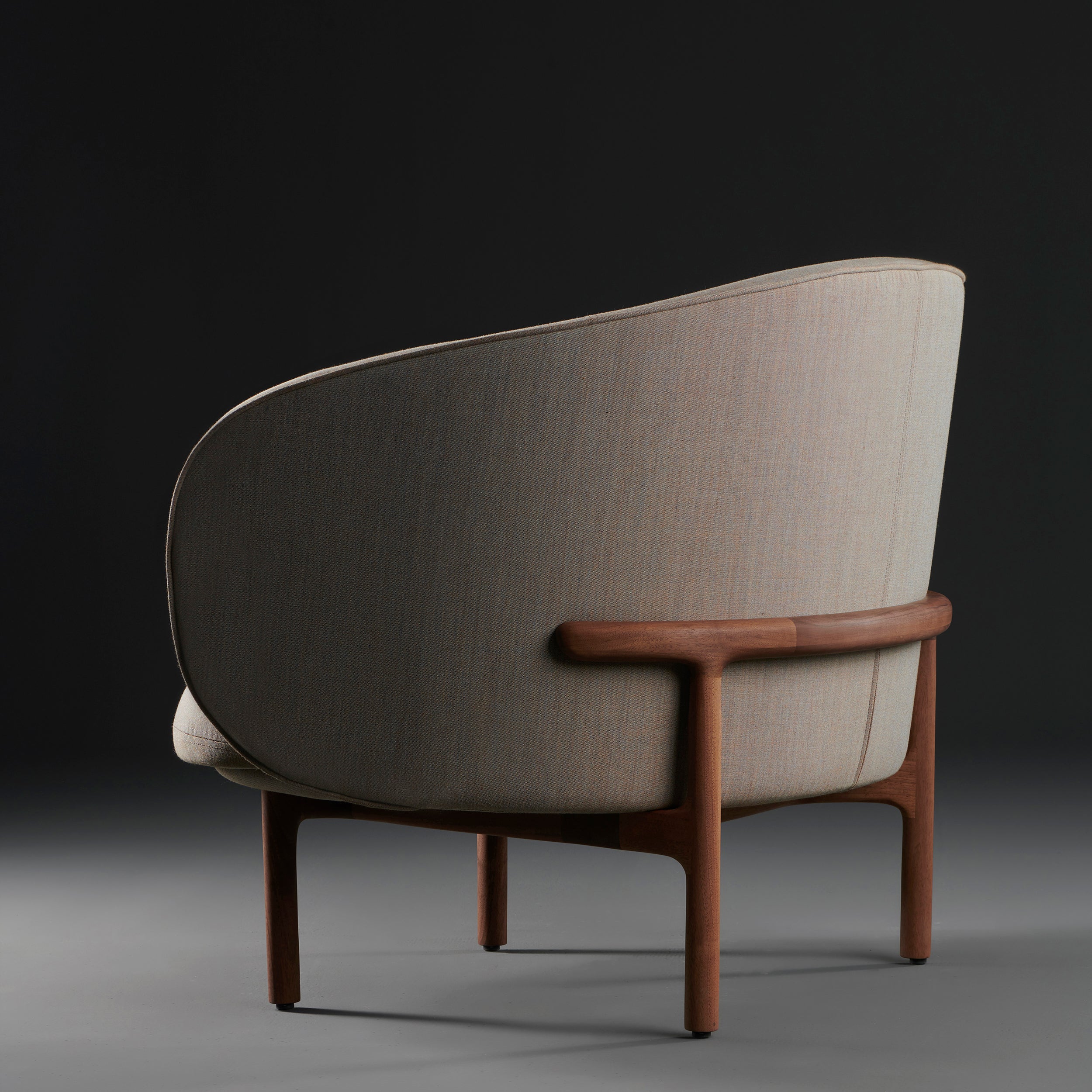 The MELA Lounge Chair Trimmed by Artisan features light grey fabric upholstery on a sleek, mid-century inspired curved shell with a dark wood frame and legs.