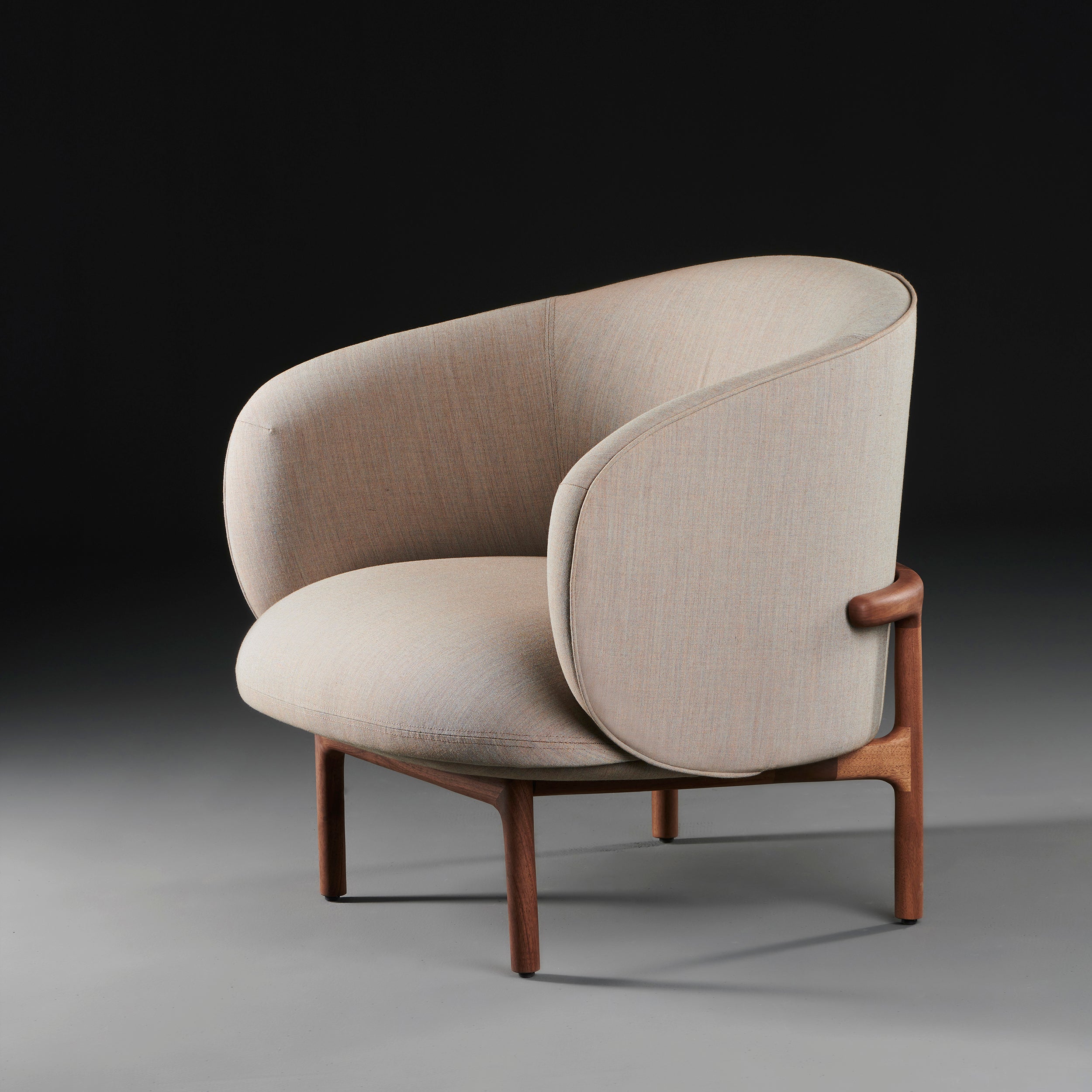 The MELA Lounge Chair Trimmed by Artisan, part of the Mela collection, features modern light beige upholstery and smooth rounded edges. Its sleek wooden frame and legs against a dark gradient backdrop showcase minimalist elegance with mid-century inspired aesthetics.