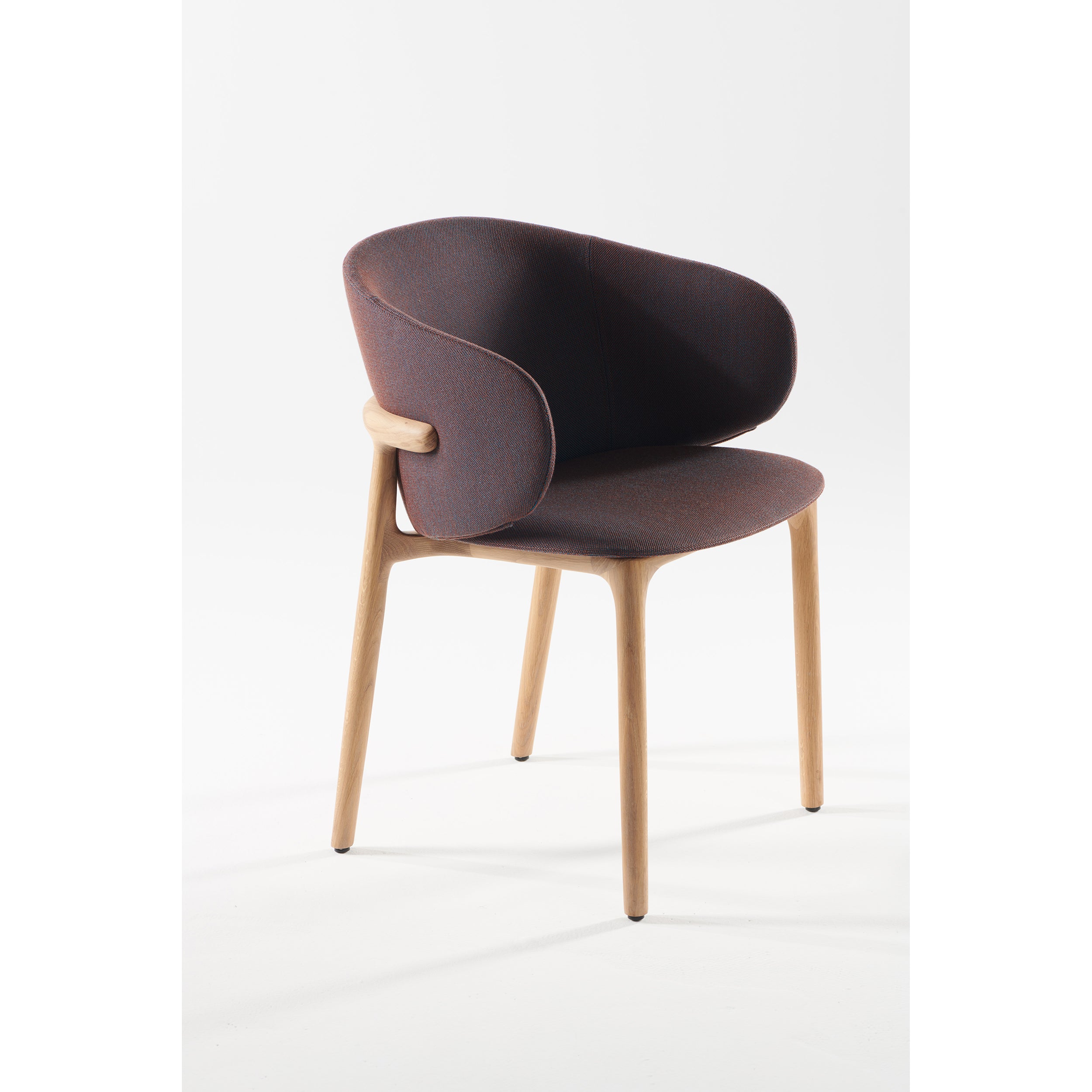 Introducing the Artisan Mela Chair, a modern design with mid-century charm. Featuring a brown cushioned seat and upholstered backrest on a light wood frame, its rounded style and four slender legs create a striking contrast against the white backdrop, merging elegance with comfort.