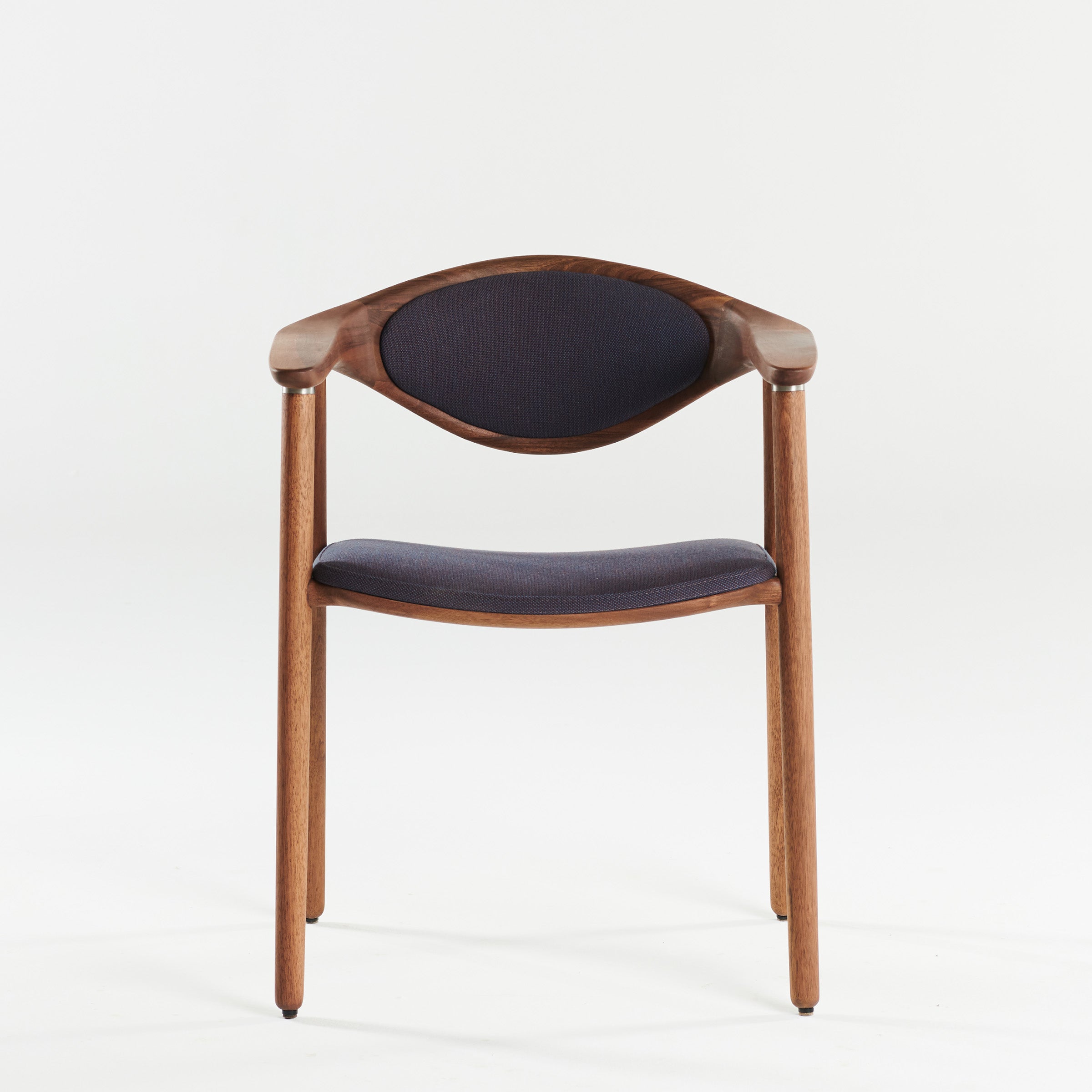 The NARU Chair by Artisan, made from solid wood with a curved backrest and armrests, features dark upholstered seating. Positioned against a plain white background and finished with natural oils, it is both environmentally-friendly and stylish.