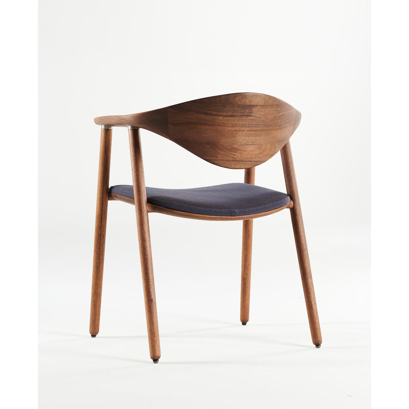 The Artisan NARU Chair features a solid wood structure with a curved backrest and four tapered legs. Its minimalist design includes a dark cushioned seat, crafted from natural materials and finished with eco-friendly oils, all set against a plain white backdrop.