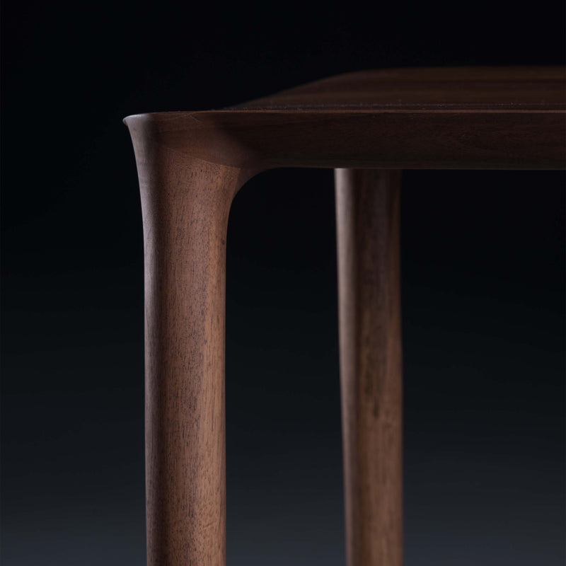 Close-up of a NEVA Stool corner and leg by Artisan against a dark background, highlighting its smooth, rounded edges and polished surface that accentuate the handcraft and natural grain of the wood.