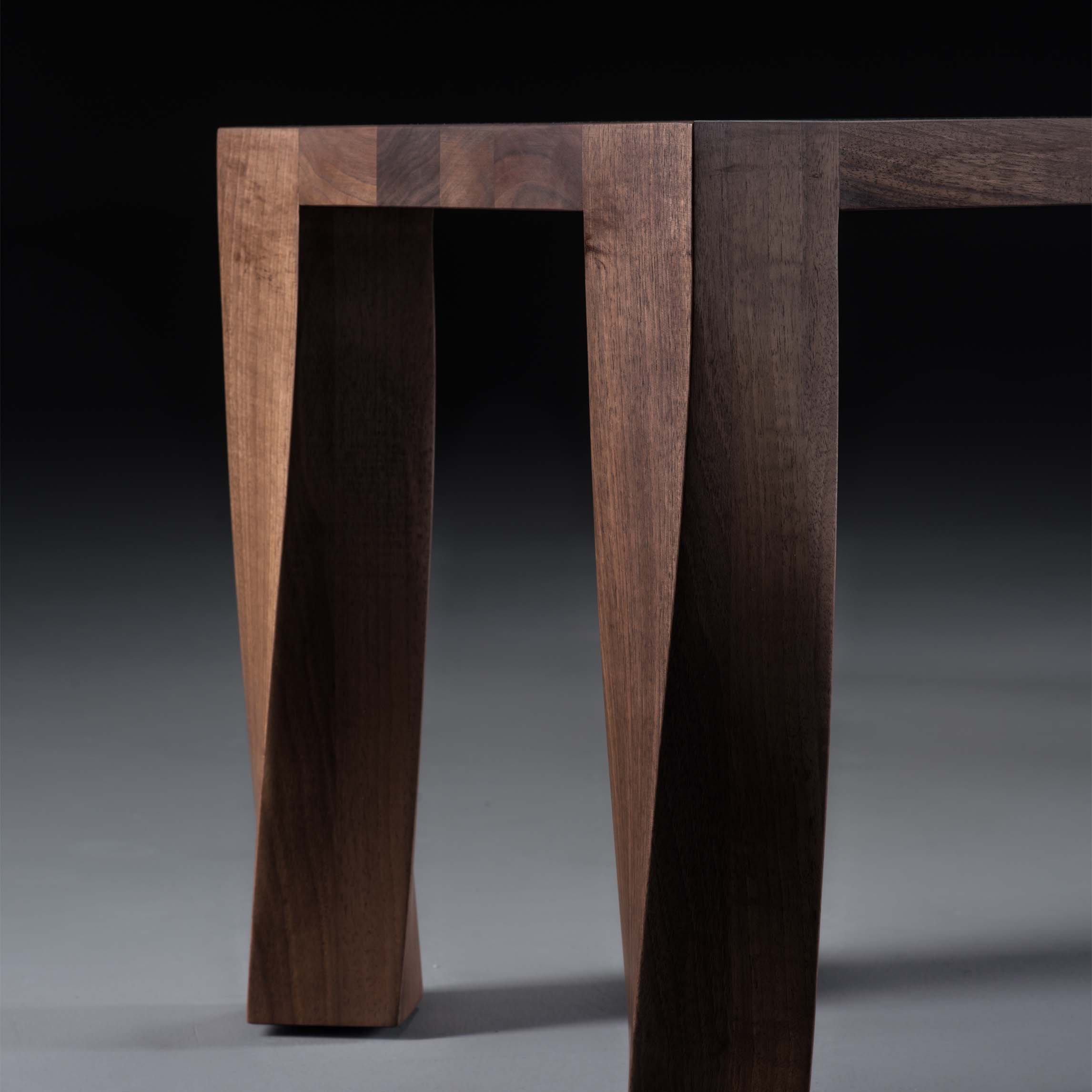 The Artisan TOR Bench features elegantly angled legs and a sleek, natural oil-enhanced finish. Its rich wood grain and modern design stand out beautifully against a dark background.