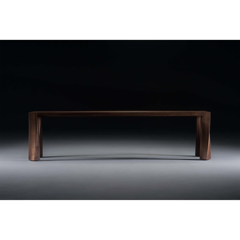 The Artisan TOR Bench, crafted from solid wood, stands out against a dark background with its four sturdy legs and smooth surface enhanced by natural oils, elegantly showcasing its minimalist and eco-friendly design.