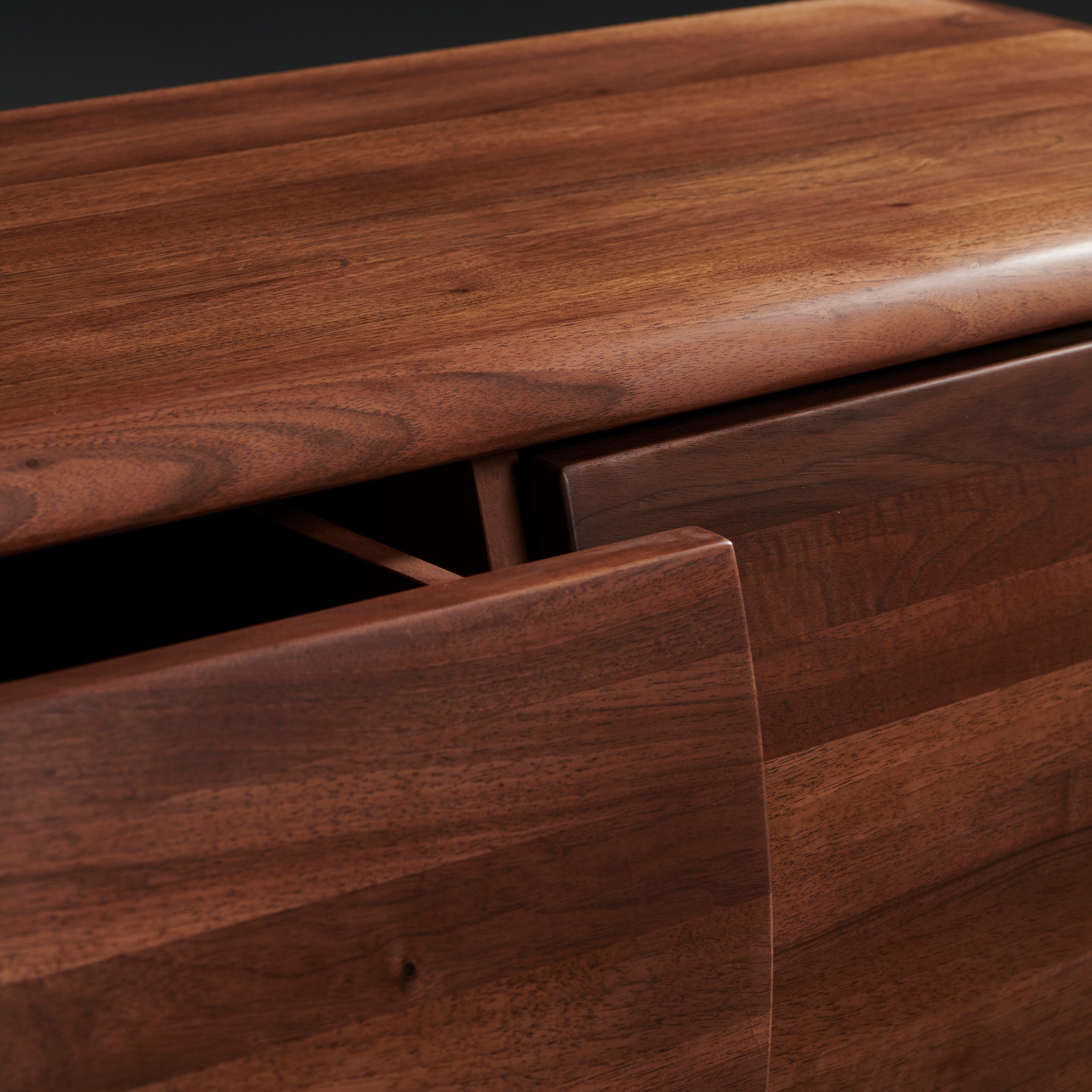 The WU Sideboard by Artisan features a polished, rich dark brown surface showcasing the organic texture of solid wood. Its slightly open door reveals a shadowed interior, highlighting its environmentally-friendly materials with visible grain patterns.