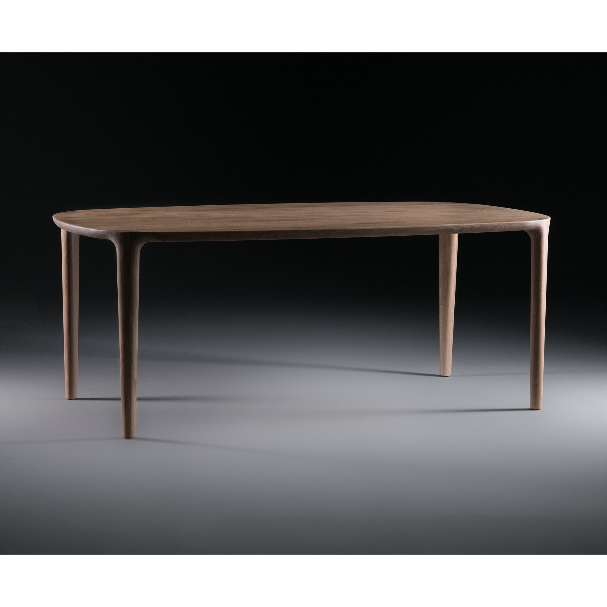 The Artisan WU Table is a sleek wooden table crafted from solid wood, featuring smooth, rounded edges and four slender legs, set against a dark background.