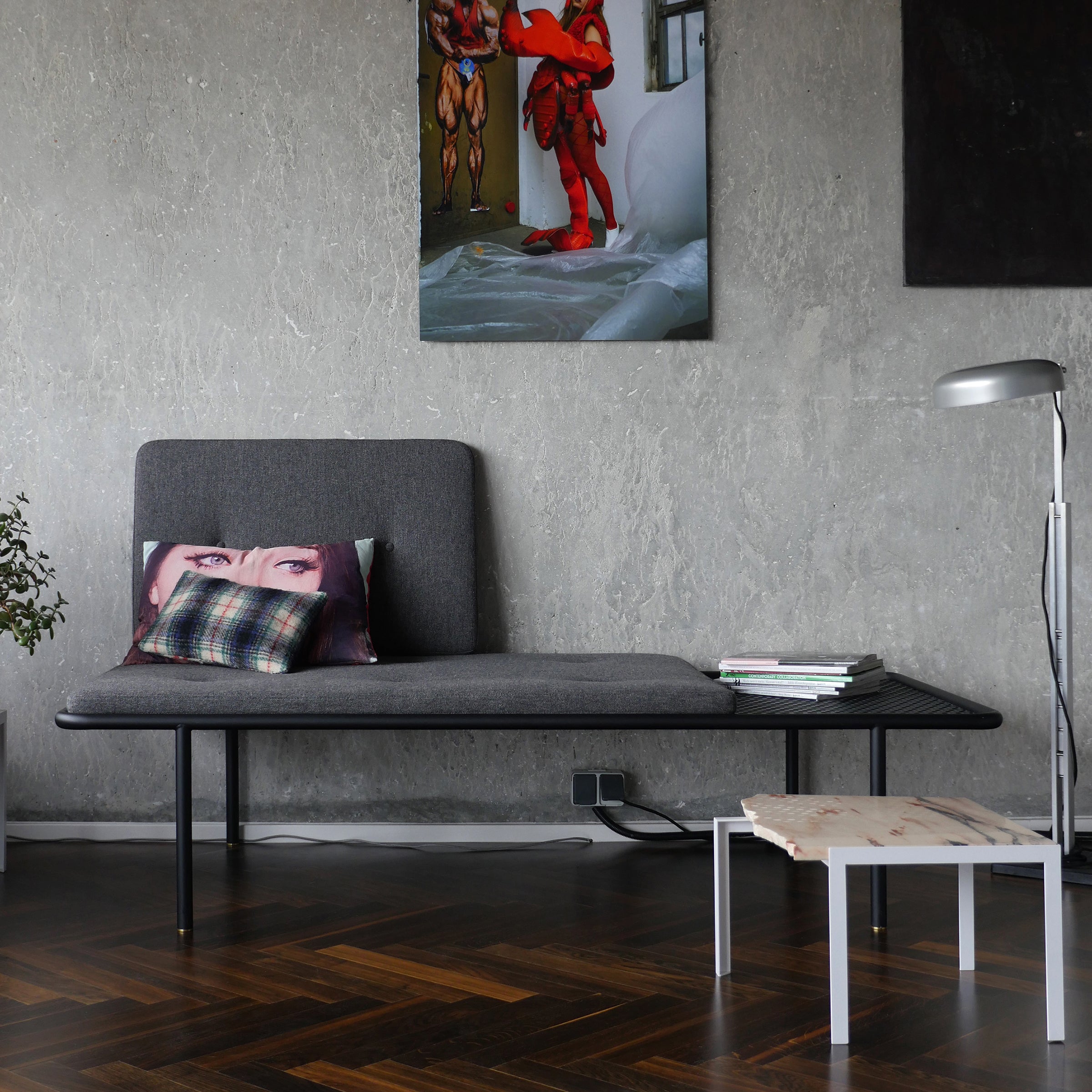 2PM Day & Night Daybed shown in modern setting with grey upholstery, black frame, and attached side table on dark hardwood floor