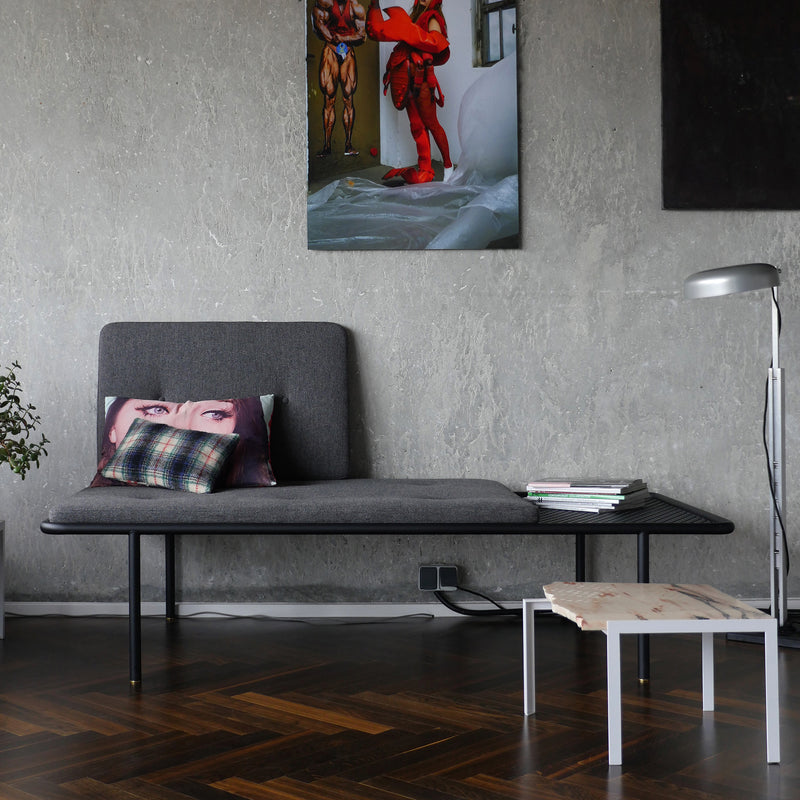 2PM Day & Night Daybed shown in modern setting with grey upholstery, black frame, and attached side table on dark hardwood floor