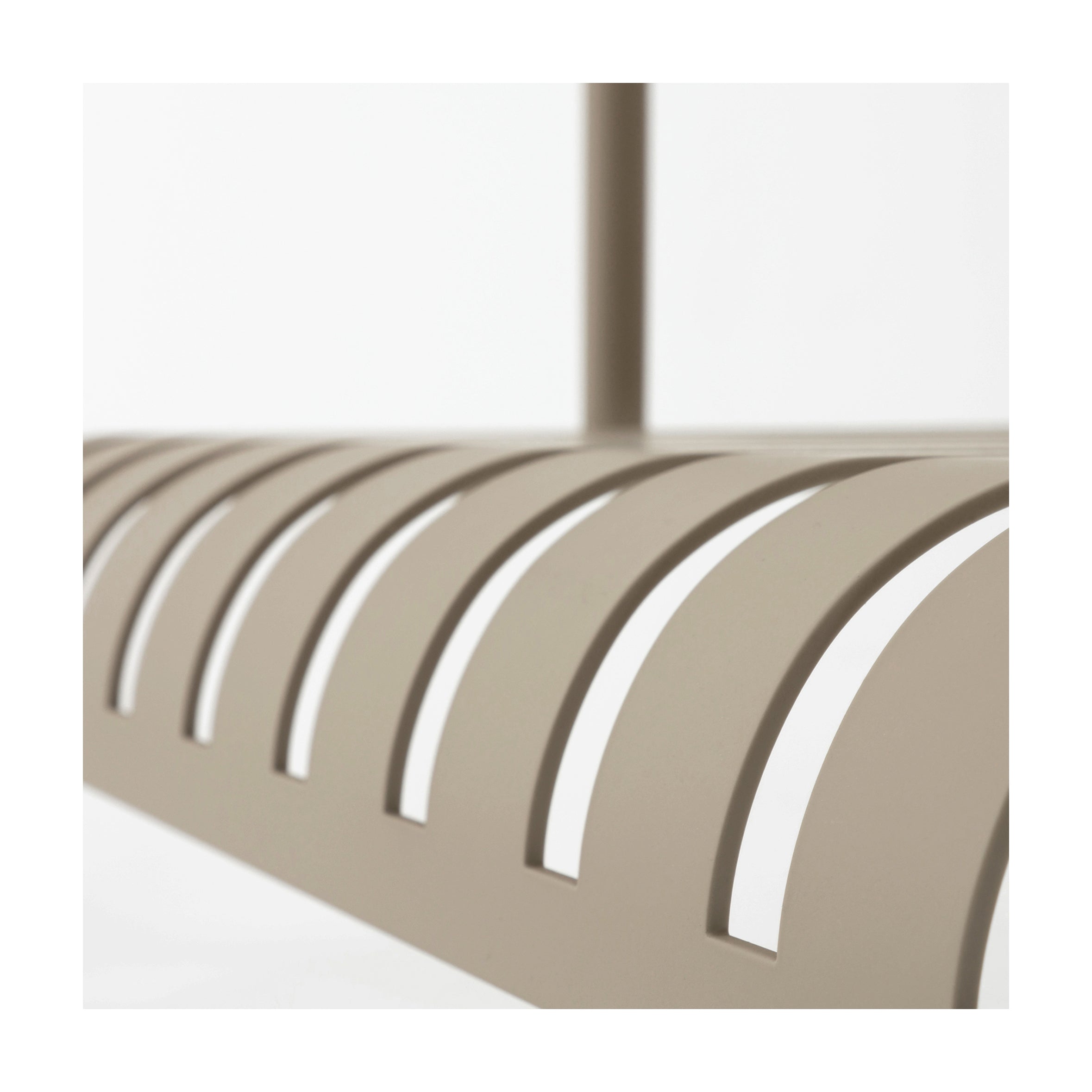 A close-up of the YOUTOO by Atelier Haussmann reveals a beige powder-coated steel structure with evenly spaced, curved slats forming parallel arches, highlighted against a soft white background.