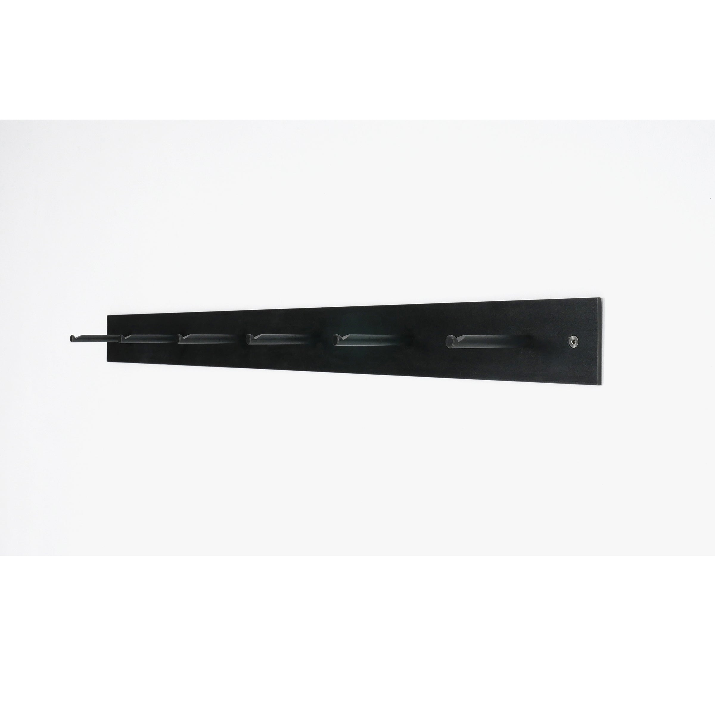 Atelier Haussmanns HELLOGOODBYE coatrack, crafted from white powder-coated steel and featuring five evenly spaced pegs, is mounted on a white wall. This black coatrack combines sleek design with minimalist and modern aesthetics.