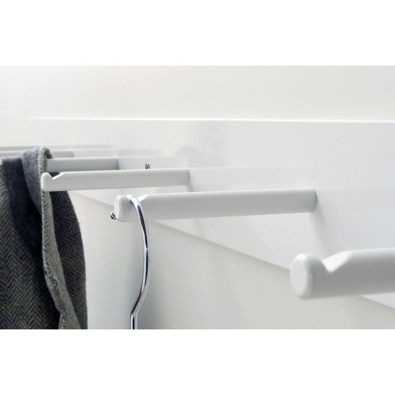 A close-up of Atelier Haussmann’s HELLOGOODBYE wall-mounted coatrack, made from white powder-coated steel, shows one metal hanger on a peg and a dark, textured fabric draped over another, capturing the linear arrangement of pegs beautifully.