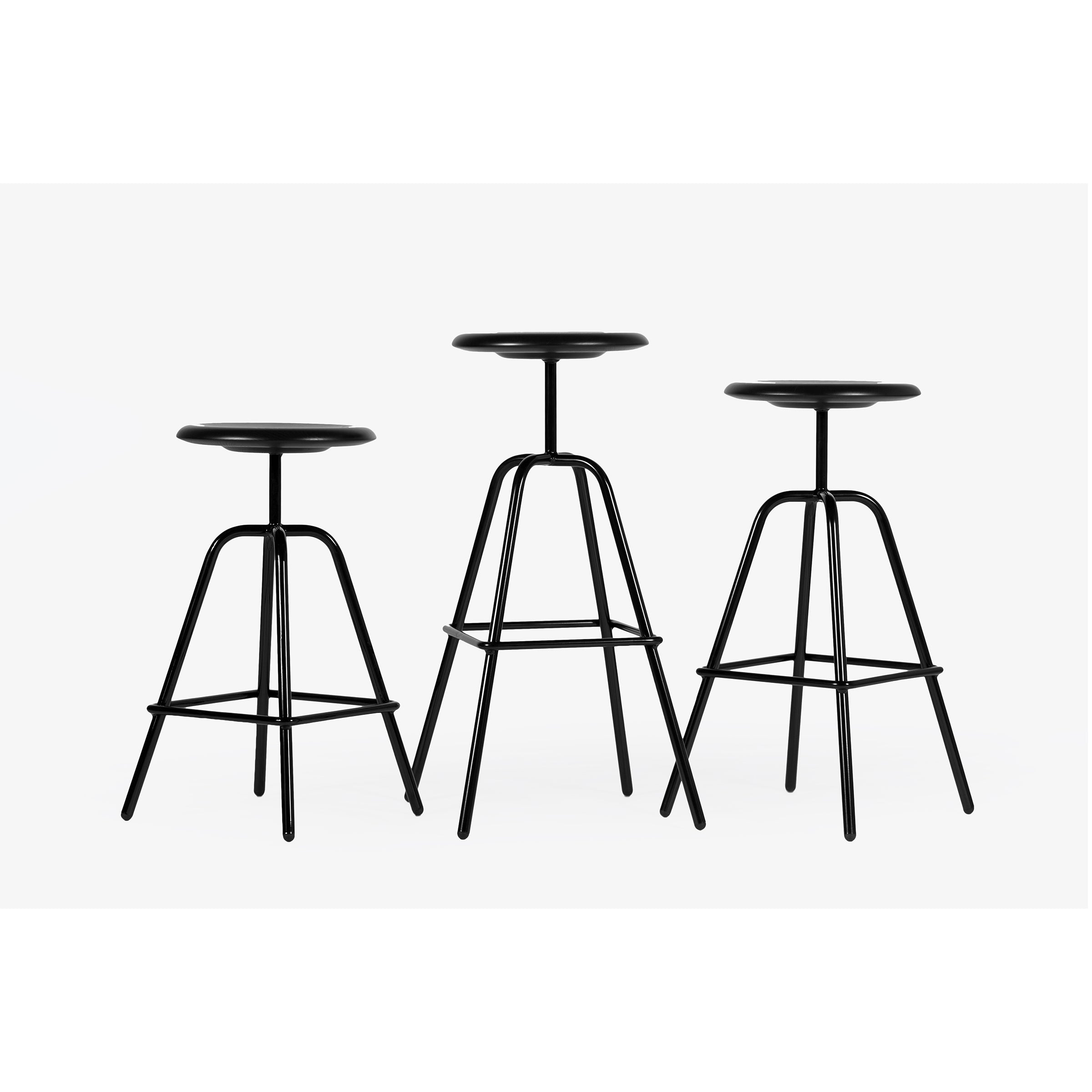 A trio of Herrenberger Barstools by Atelier Haussmann, crafted with black metal and tubular steel frames, stand against a white backdrop. These sleek stools showcase industrial elegance with their minimalist design and round seats.