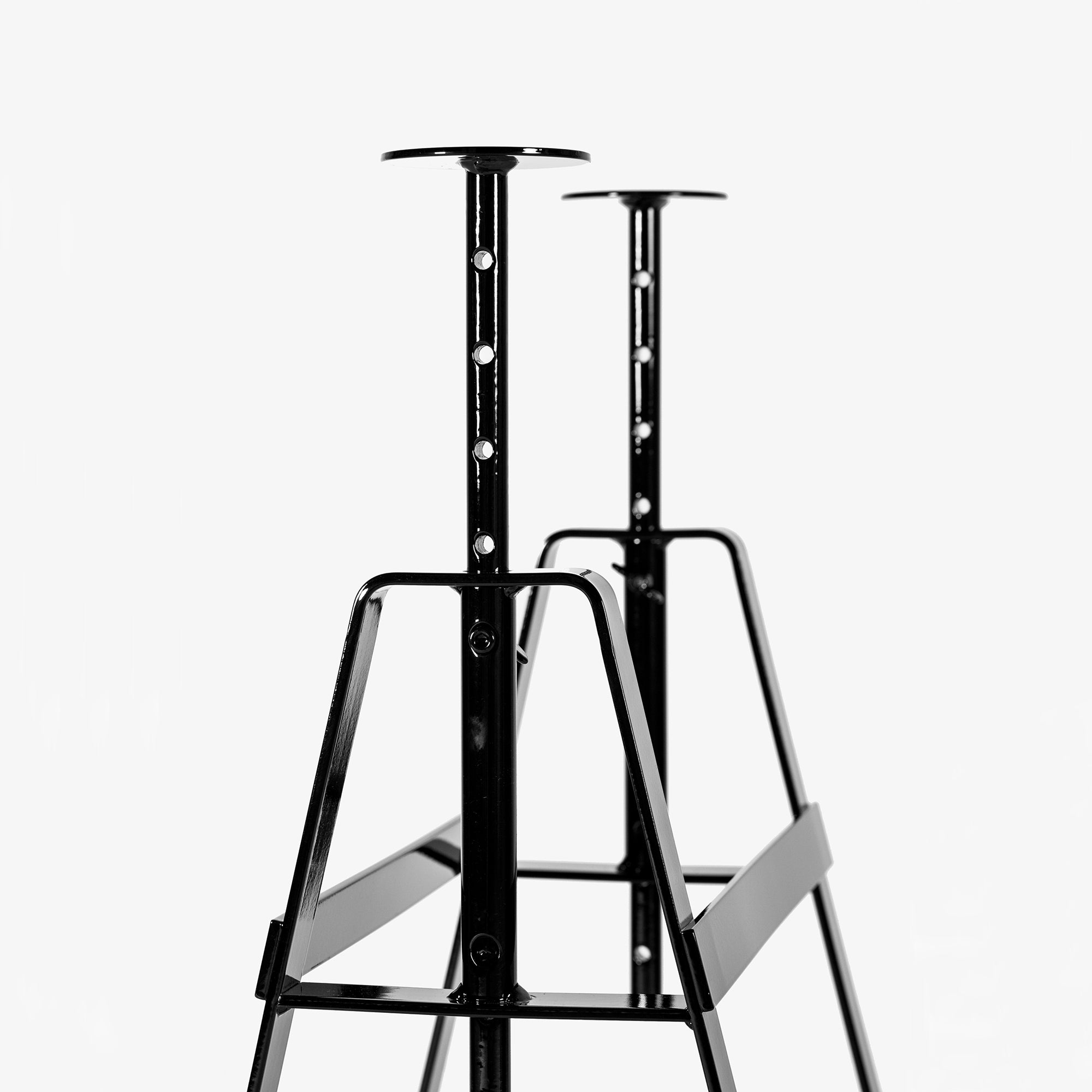 Close-up of Lackaffe Trestle: sleek, black powder-coated steel table legs with adjustable height and customizable holes. This minimalist design by Atelier Haussmann captures the essence of Berlin craft, set against a plain white background.