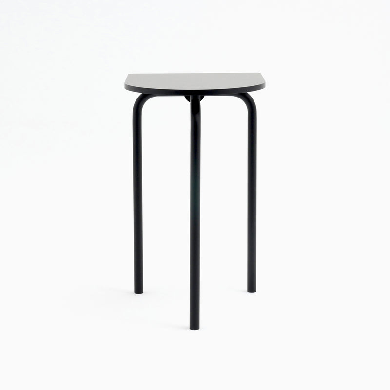 The Piombino Alto 700 by Atelier Haussmann features a minimalist design with a triangular black seat and three slender metal legs. Its sleek industrial charm complements the Piombino table perfectly in contemporary settings.