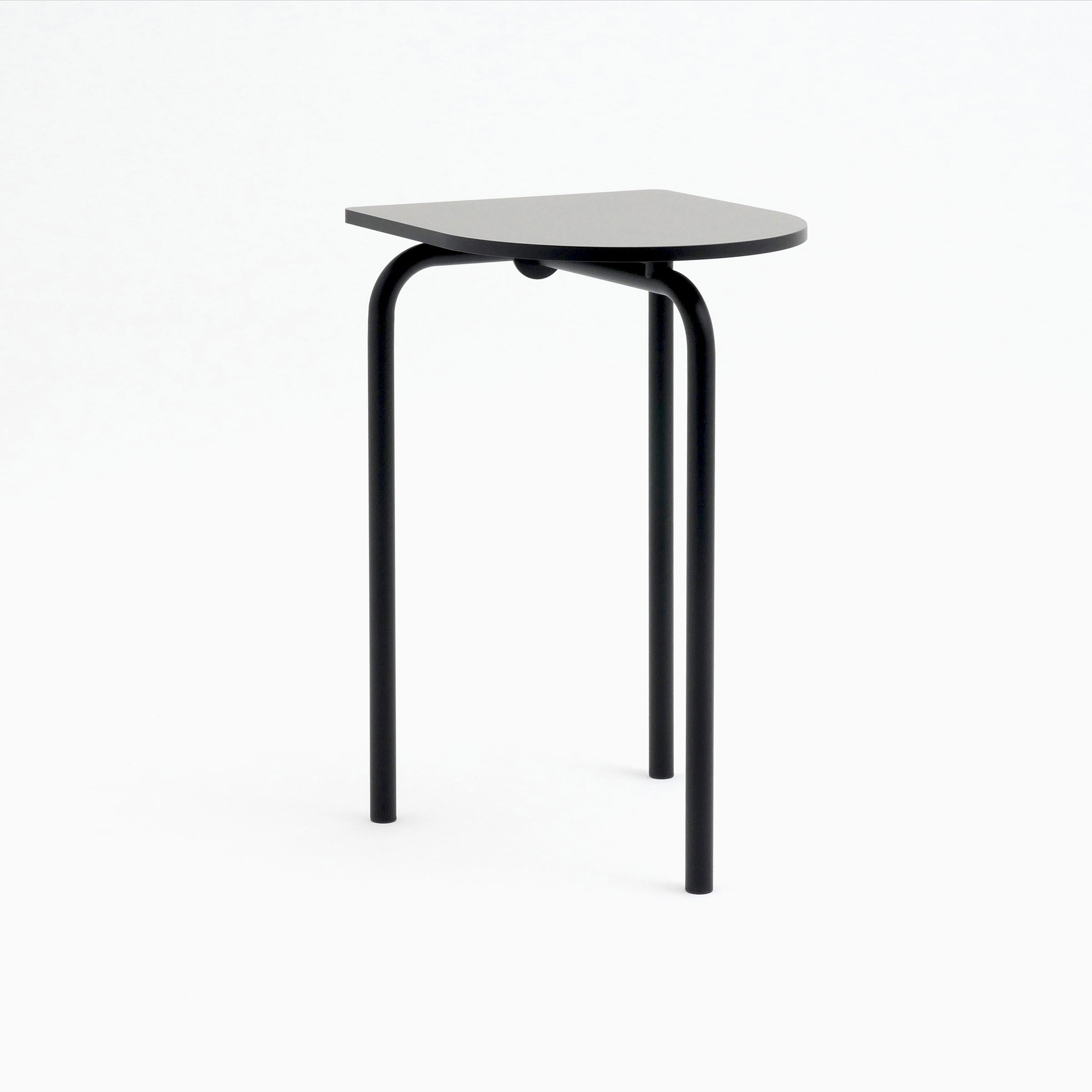 Meet the Piombino Alto 700 by Atelier Haussmann: a minimalist black side table featuring three curved metal legs and a semi-circular top. Its sleek, modern design draws from industrial aesthetics, standing gracefully against a plain white backdrop.
