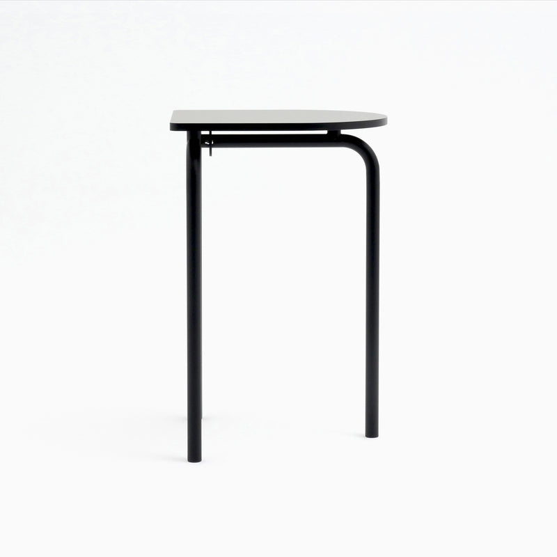 Introducing the Piombino Alto 700 table by Atelier Haussmann: a minimalist half-circle black design with industrial elegance and two sturdy legs. Ideal for modular setups, its flat edge attaches seamlessly to the wall while the curved side stands out against a white background.