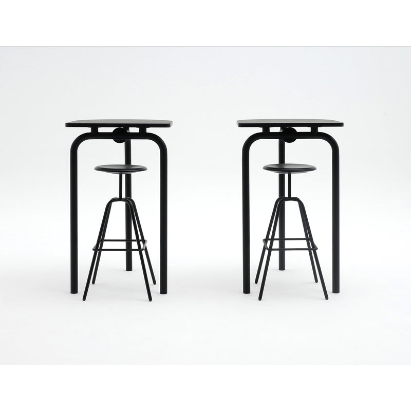 Two sleek black bar stools are set in front of matching Piombino Alto 700 tables by Atelier Haussmann, highlighting minimalist and industrial design. Each stool has a circular seat and narrow legs, while the tables feature rectangular surfaces with four slender legs.