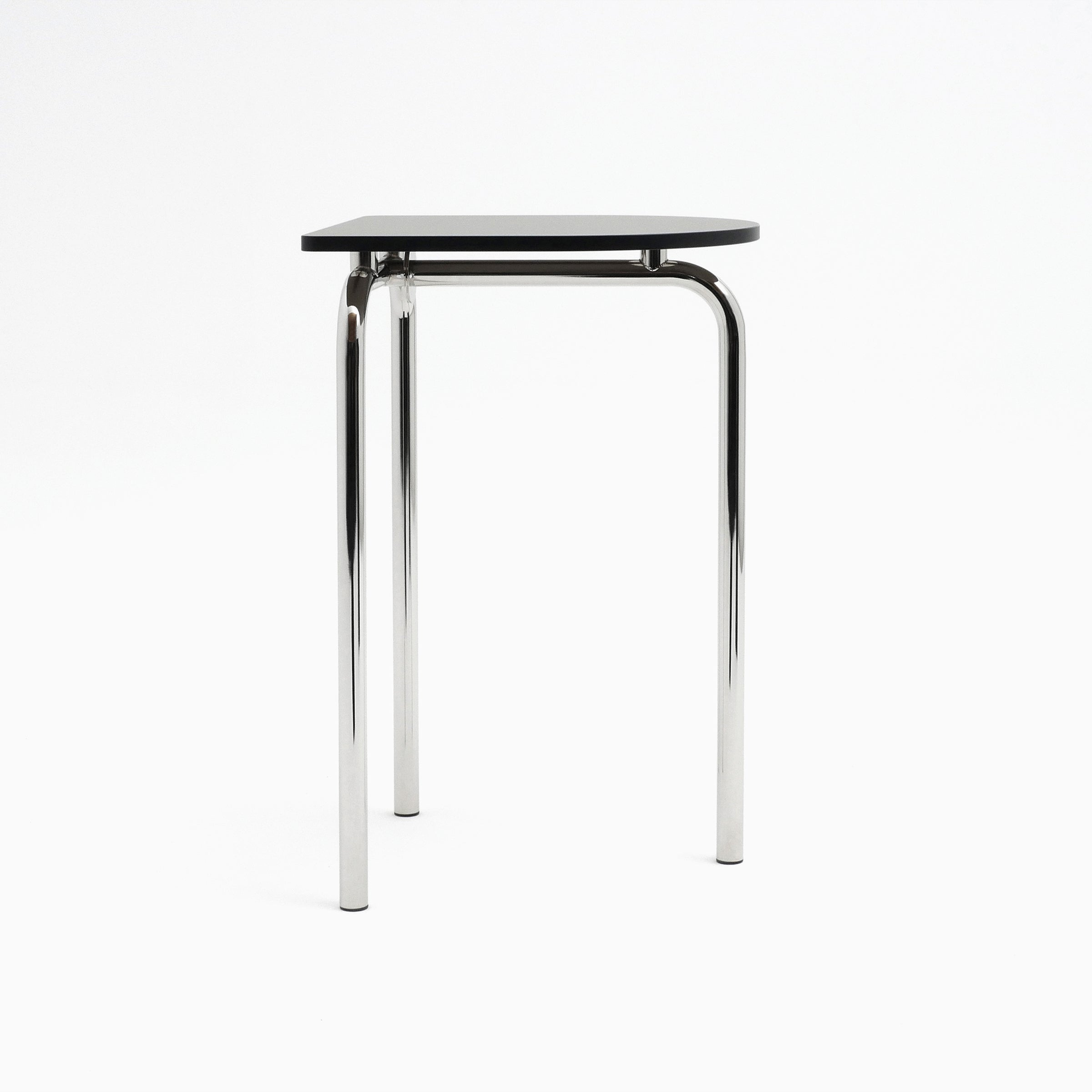 The Piombino Alto 700 by Atelier Haussmann is a minimalist table with a black triangular top and three polished chrome legs, exuding an industrial and modern aesthetic that complements any modular system.