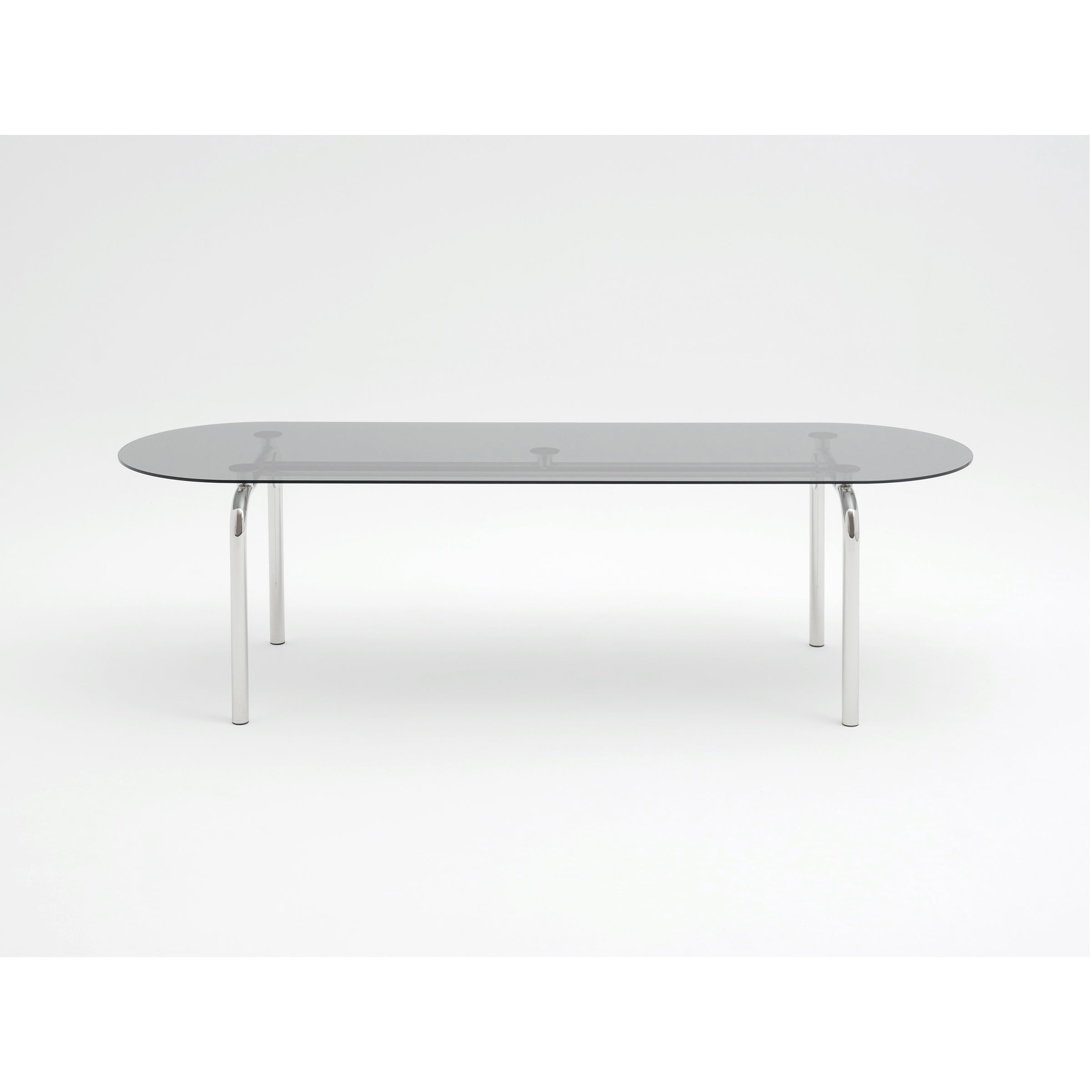 Introducing the Piombino Basso Table by Atelier Haussmann—a modern piece with a glass top, oval shape, and four slim steel tube legs. Its minimalistic design set against a white background highlights its elegant simplicity and modular system.