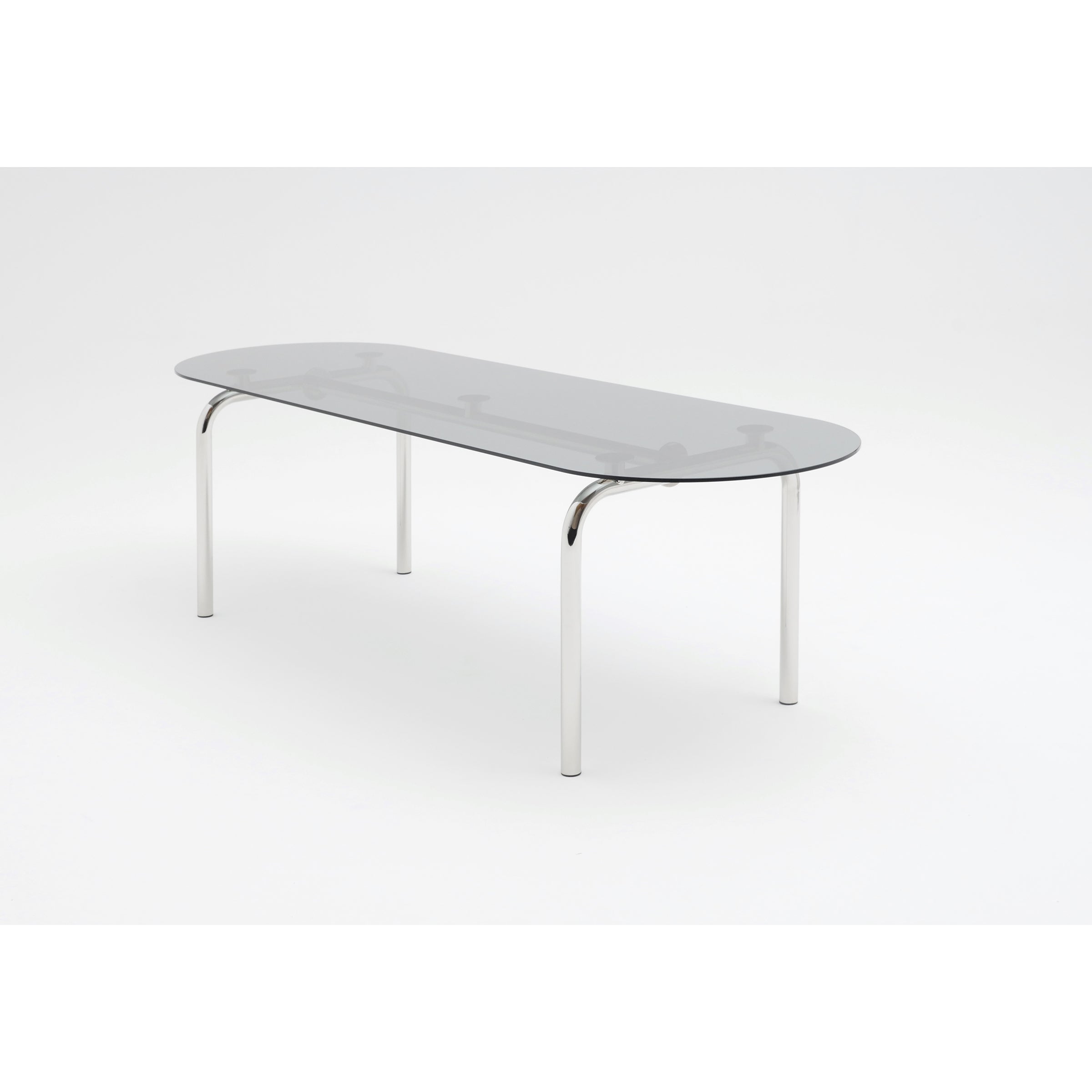 Introducing the Piombino Basso Table by Atelier Haussmann: a modern, minimalist design with a sleek rectangular glass top and rounded corners. Supported by four shiny curved steel legs, it offers a light, airy appeal against a white background—ideal for modular system setups.