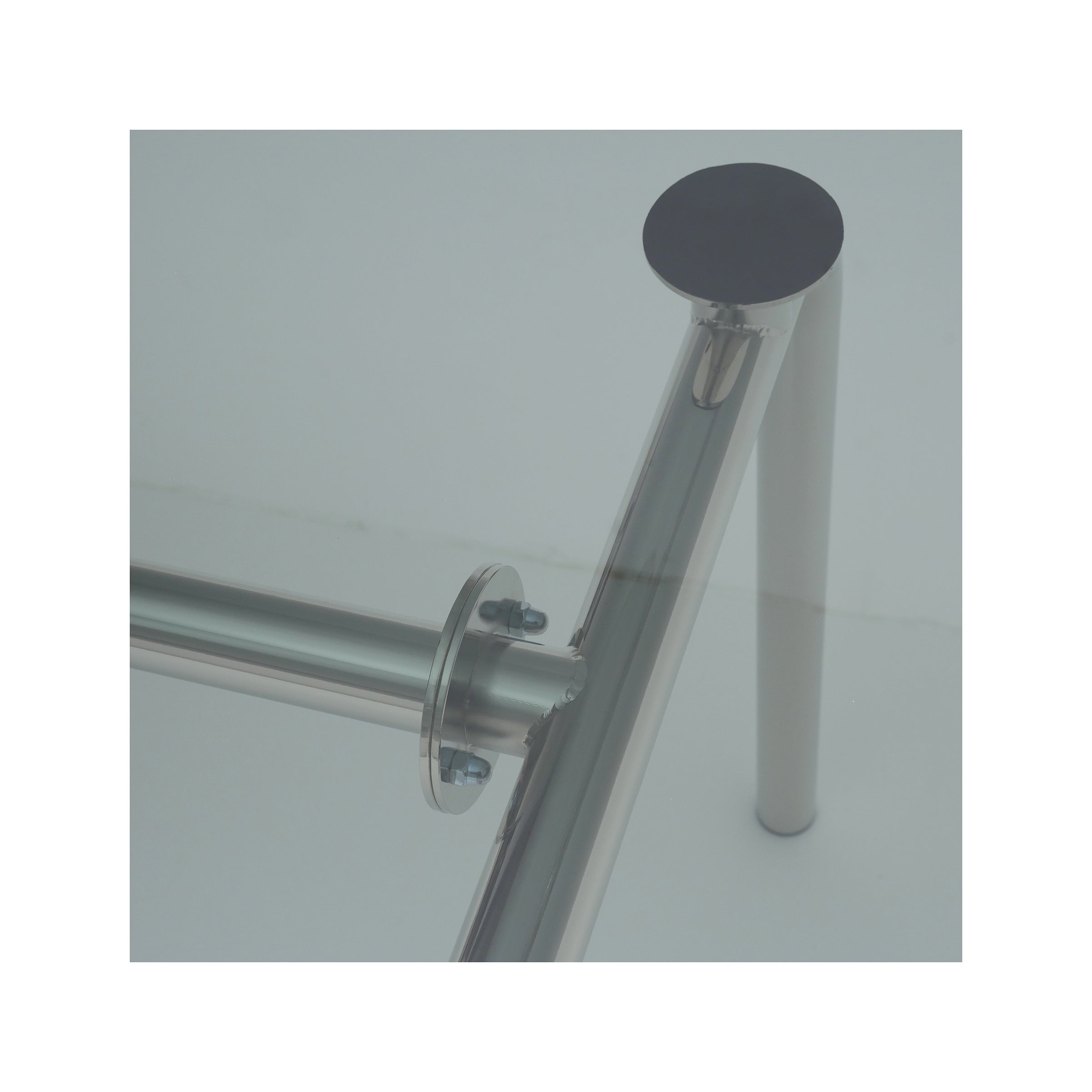 Close-up of an Atelier Haussmann Piombino Basso Table frame made from steel tubes, highlighted by cylindrical legs and round joints, on a plain, light-colored background.